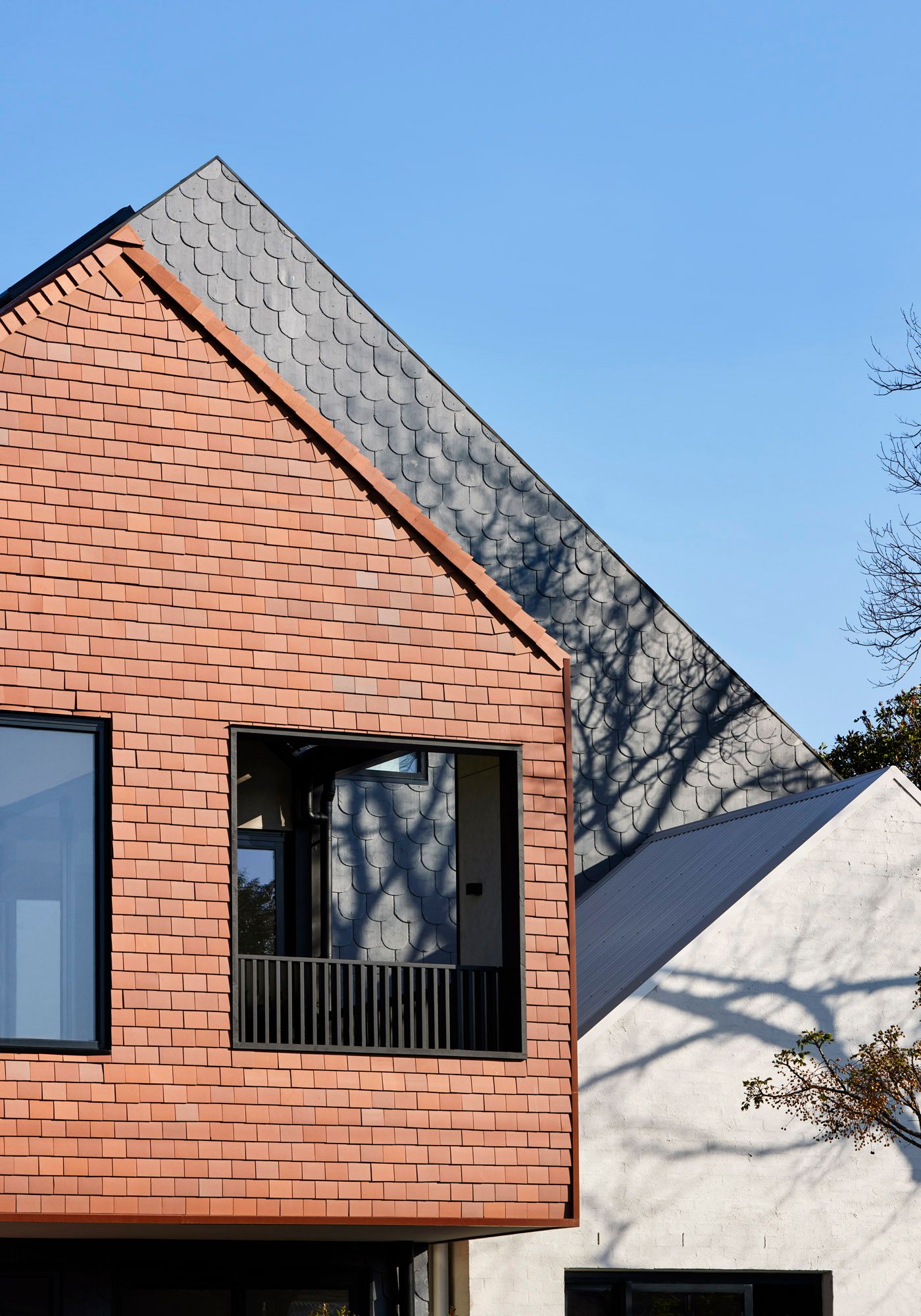 Slate House by Austin Maynard Architects. Exterior facade view, detailing terracotta wall cladding and clay roof tiles