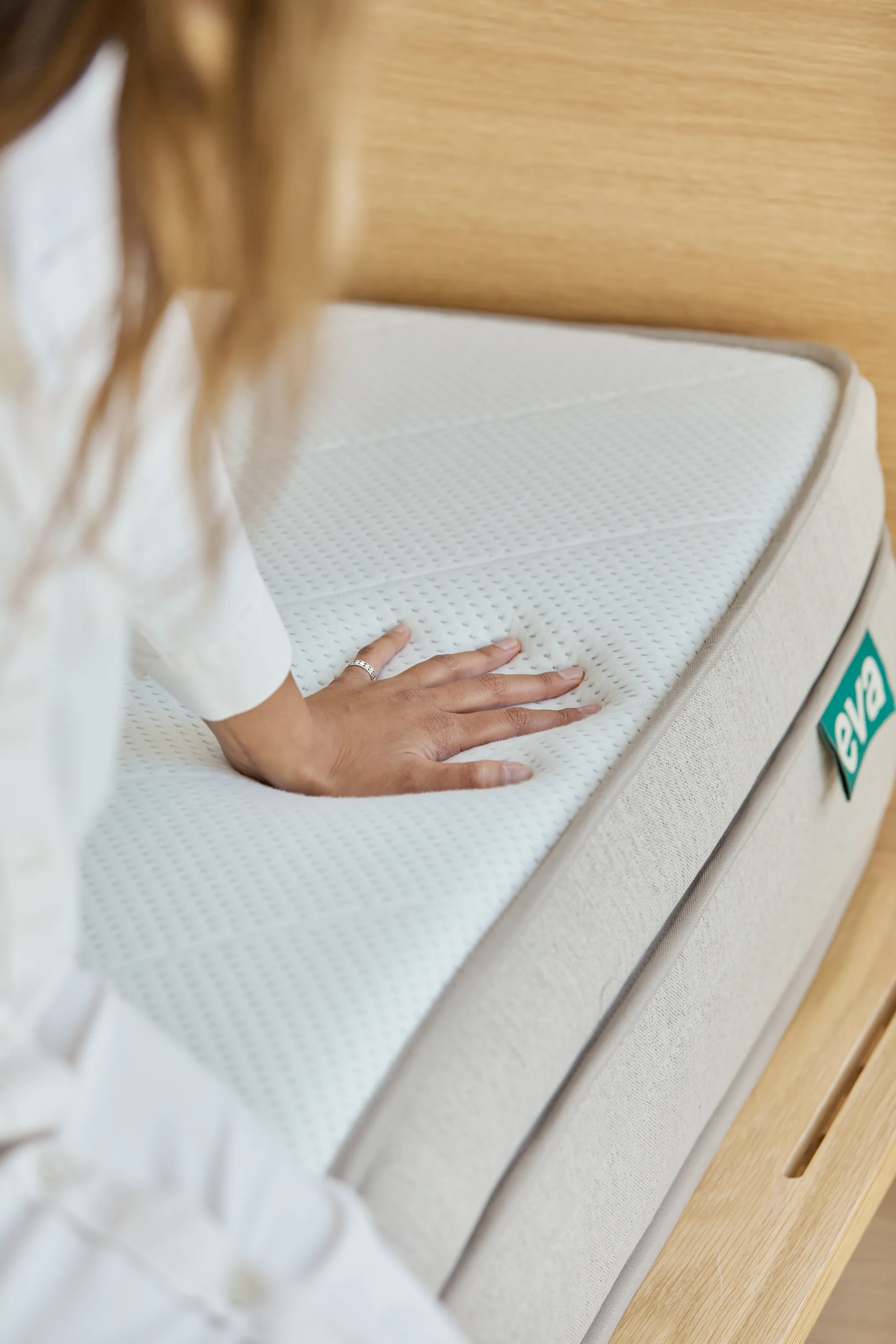 The Premium Adapt Mattress by Eva with person sitting and feeling the mattress