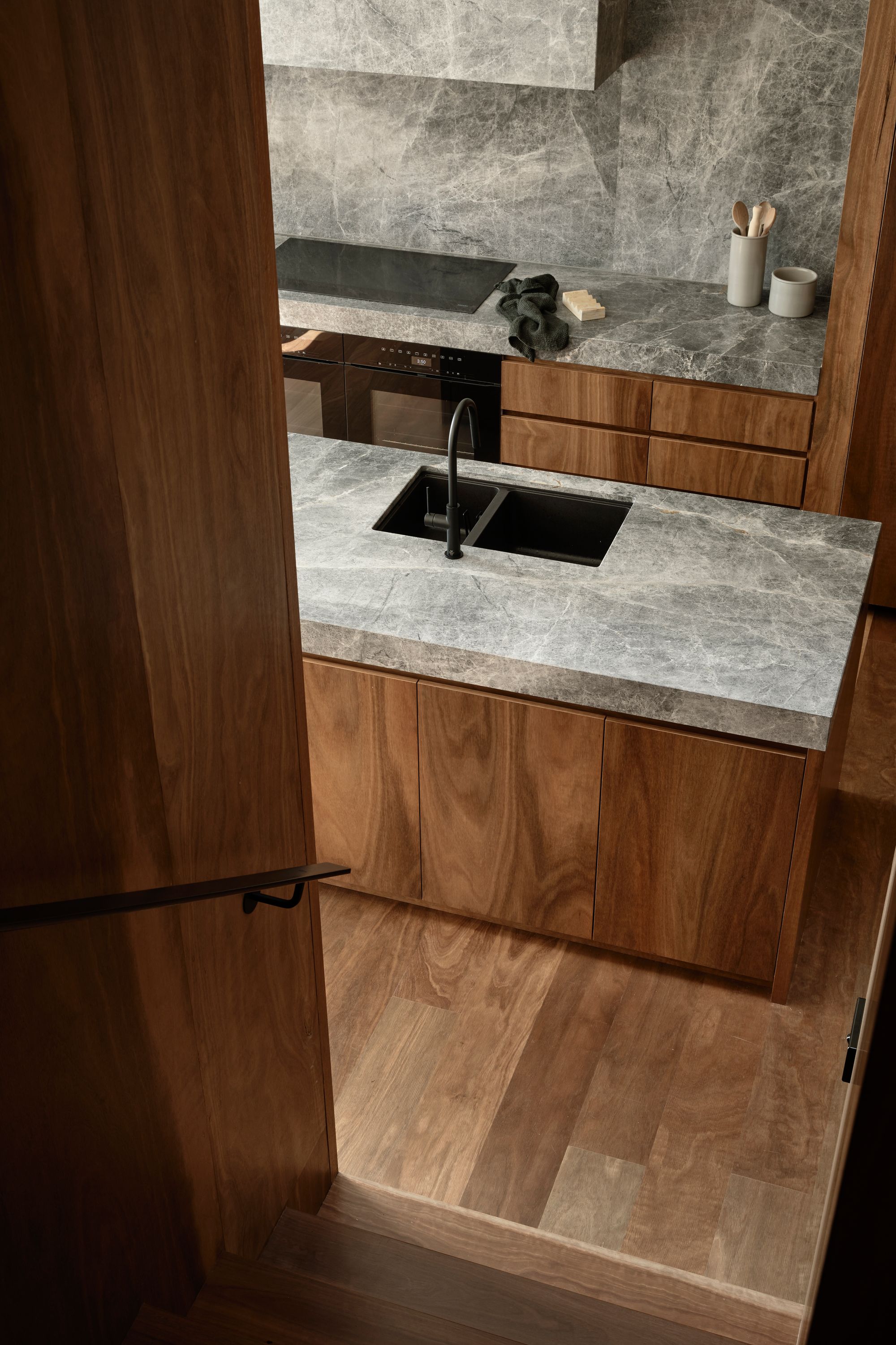Carlton North Residence by Project 12 Architecture. Detail view of Kitchen, featuring big river joinery & G-lux stone
