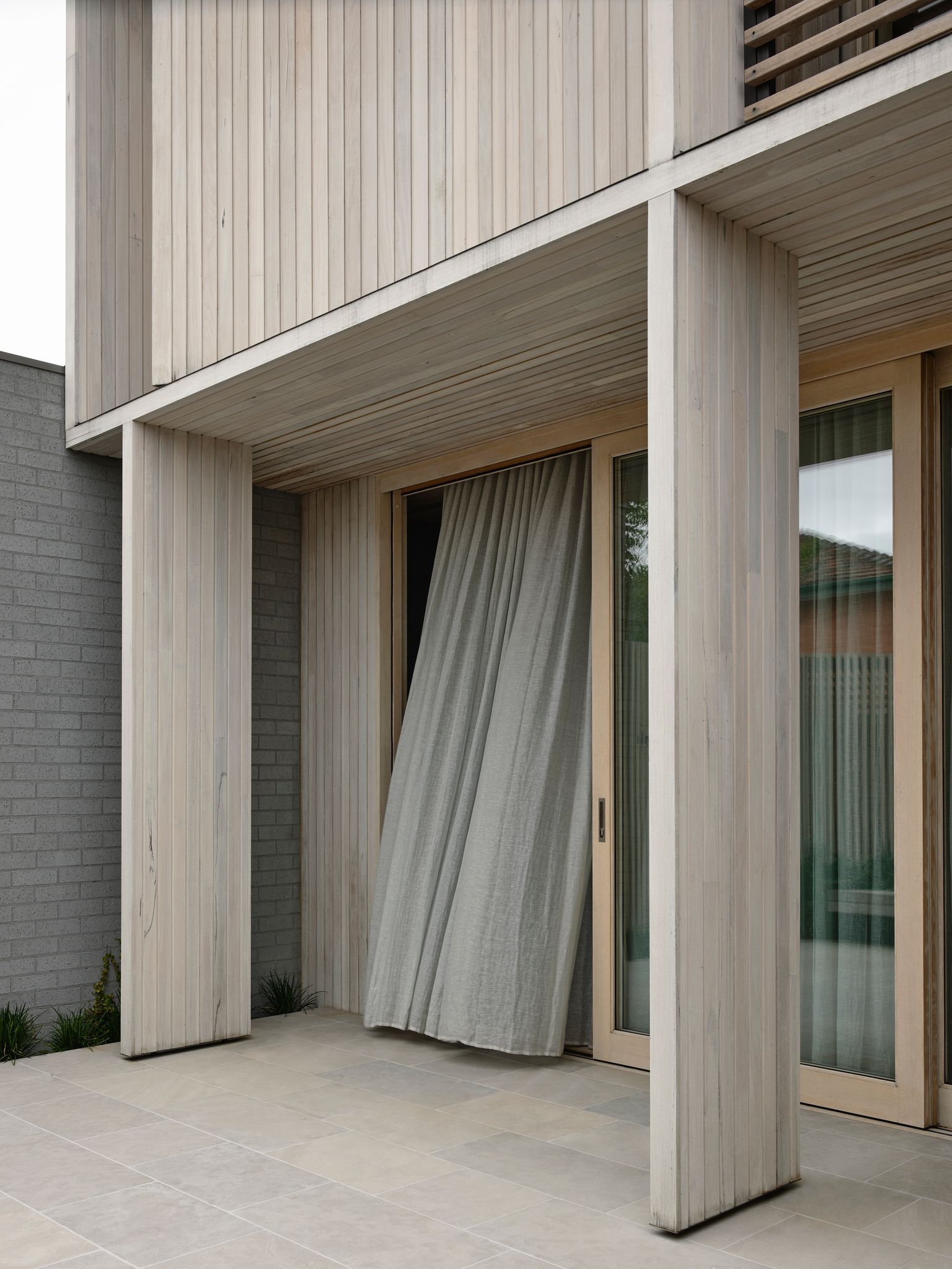 Silvertop House by Tom Robertson Architects. Broad timber-framed sliding doors connect the lounge to the rear garden terrace