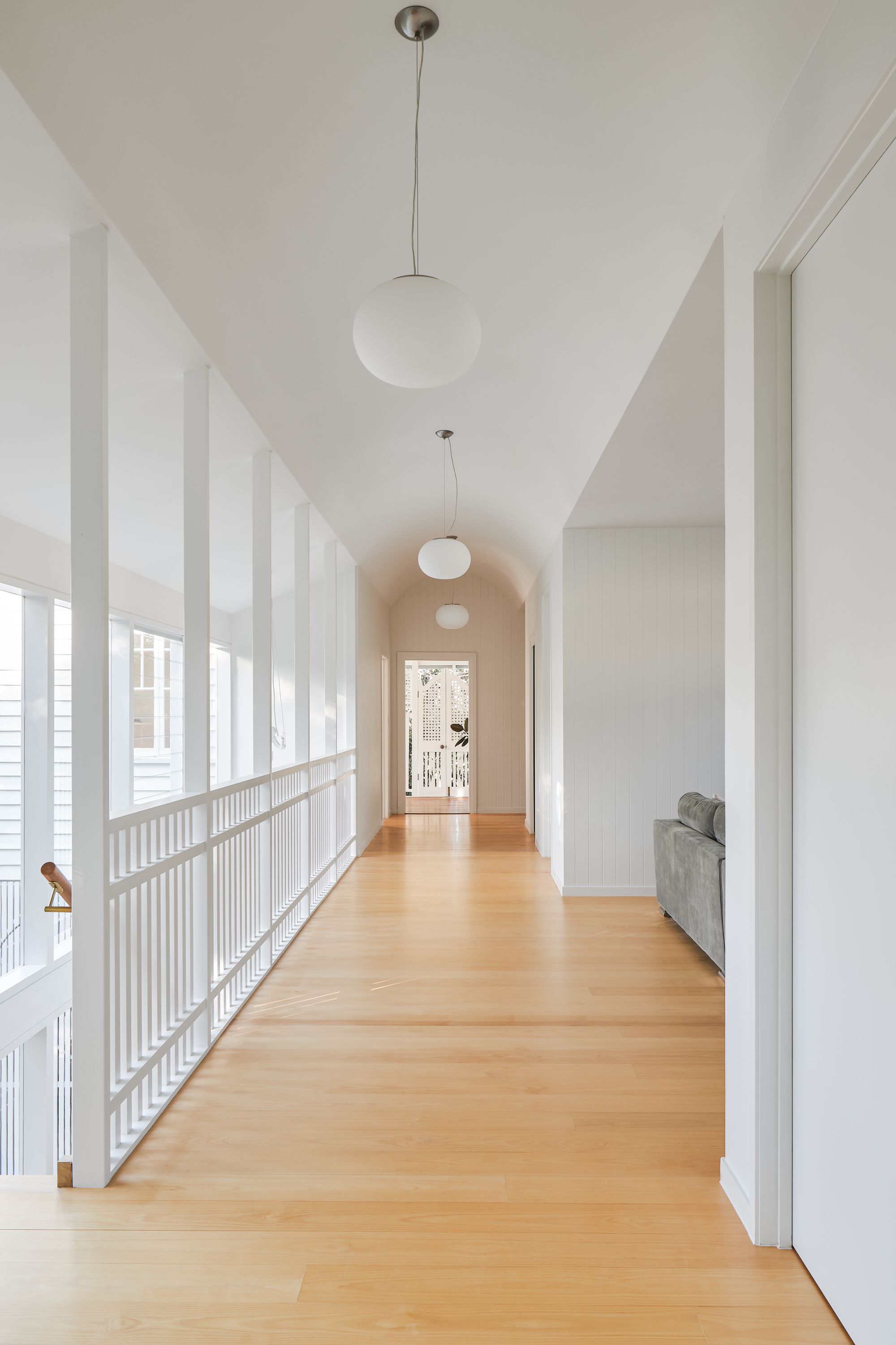Fuller Street Cottage by DAH Architecture showing internal hallway with timber flooring and pendant lights