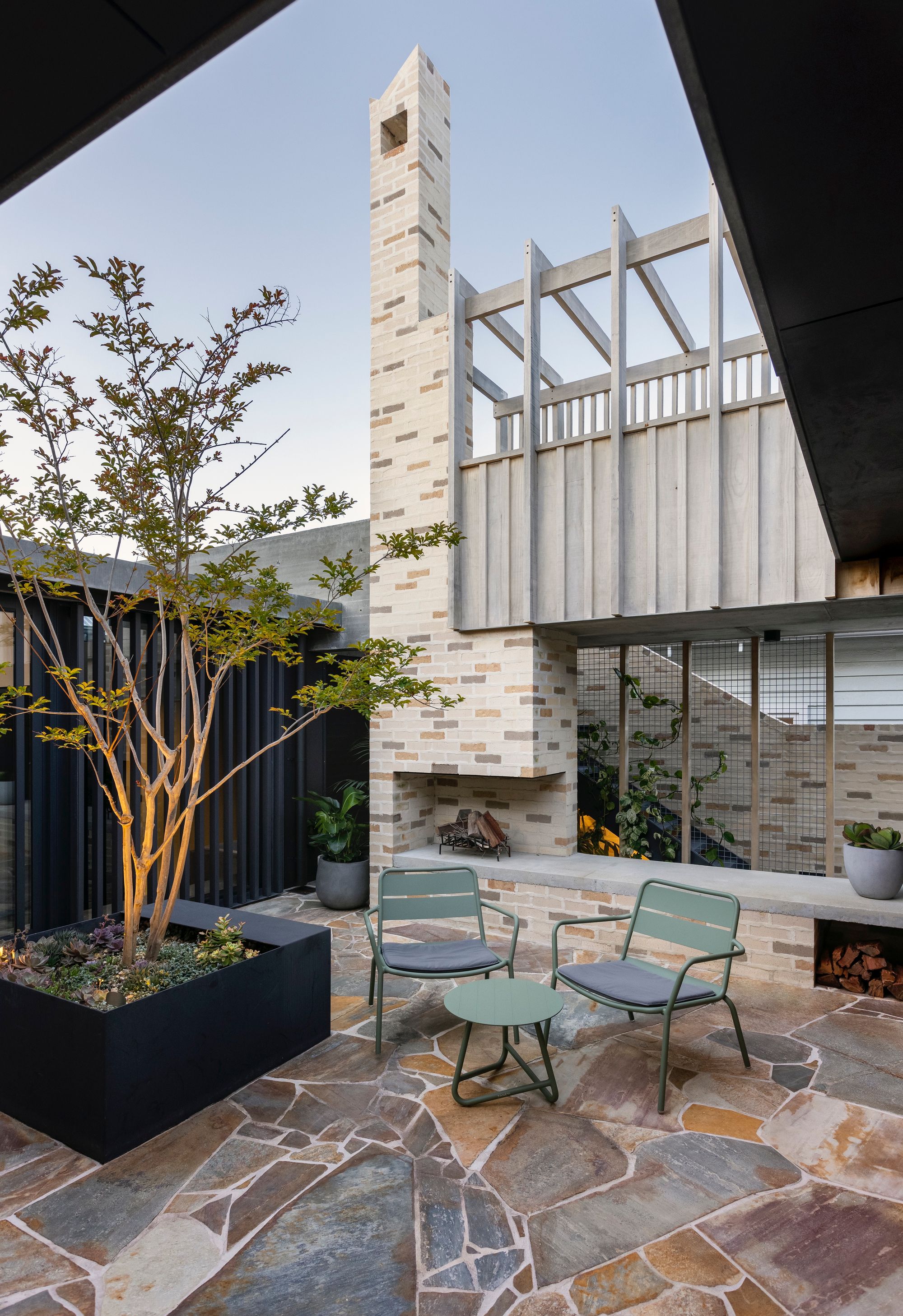 Higham Road by Philip Stejskal Architecture showing internal paved courtyard with large brick outdoor fireplace and seating
