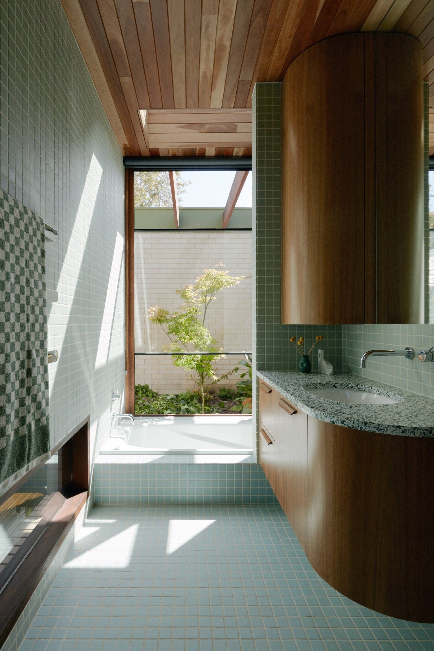 Florida House by Nest Archi. Mid century bathroom with green tiles and wood basin features. 