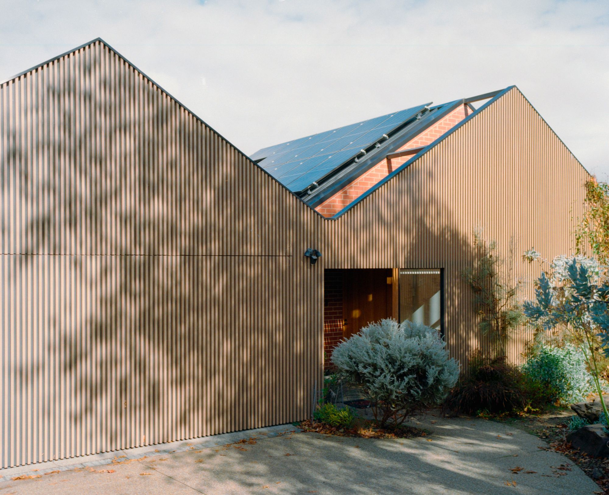 Amy Street residence by Neil Architecture. Facade of home featured from driveway entrance. 