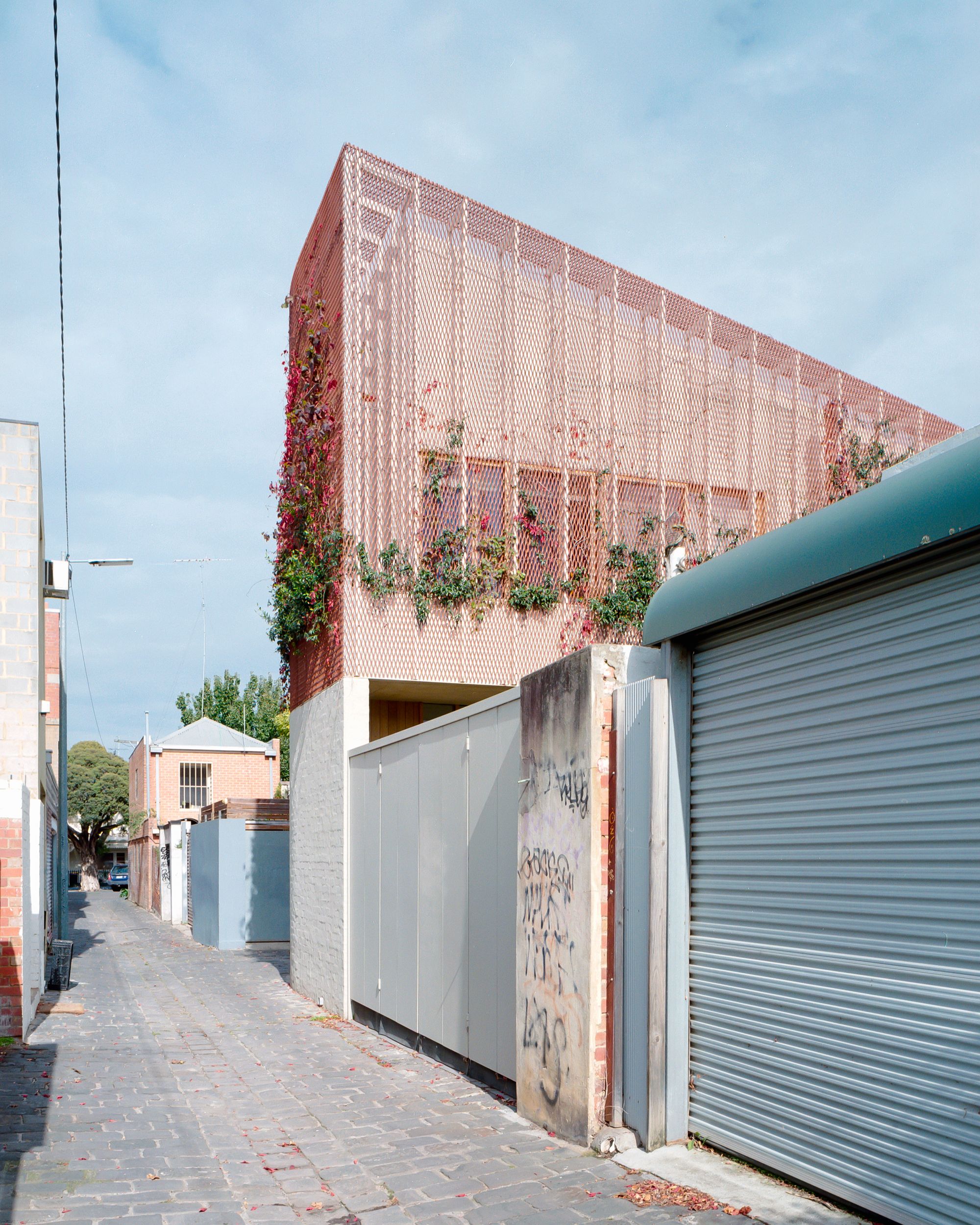 Autumn House by Studio Bright. Street view from rear of home, Contrasting tones of red and blue 