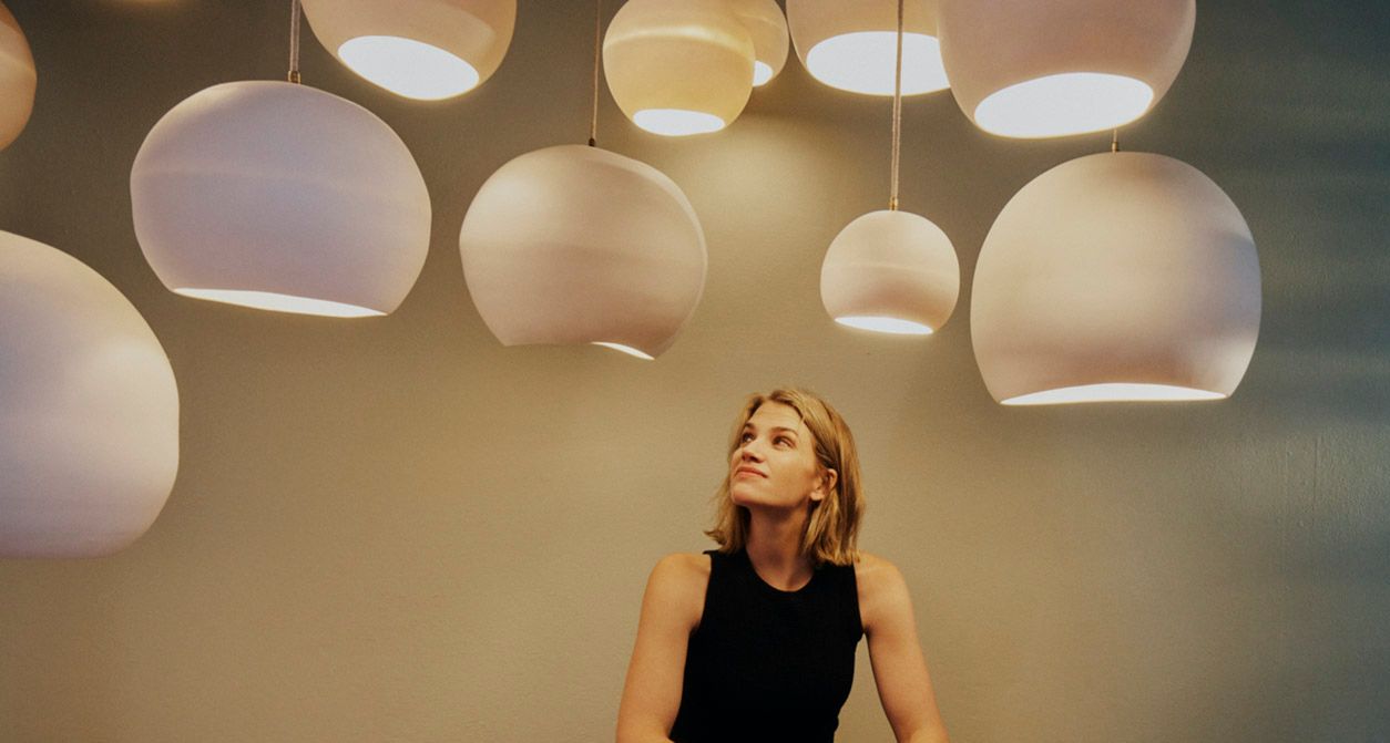 Studio Enti Founder Naomi Taplin surrounded by a range of small to large Orb Pendant Lighting. 