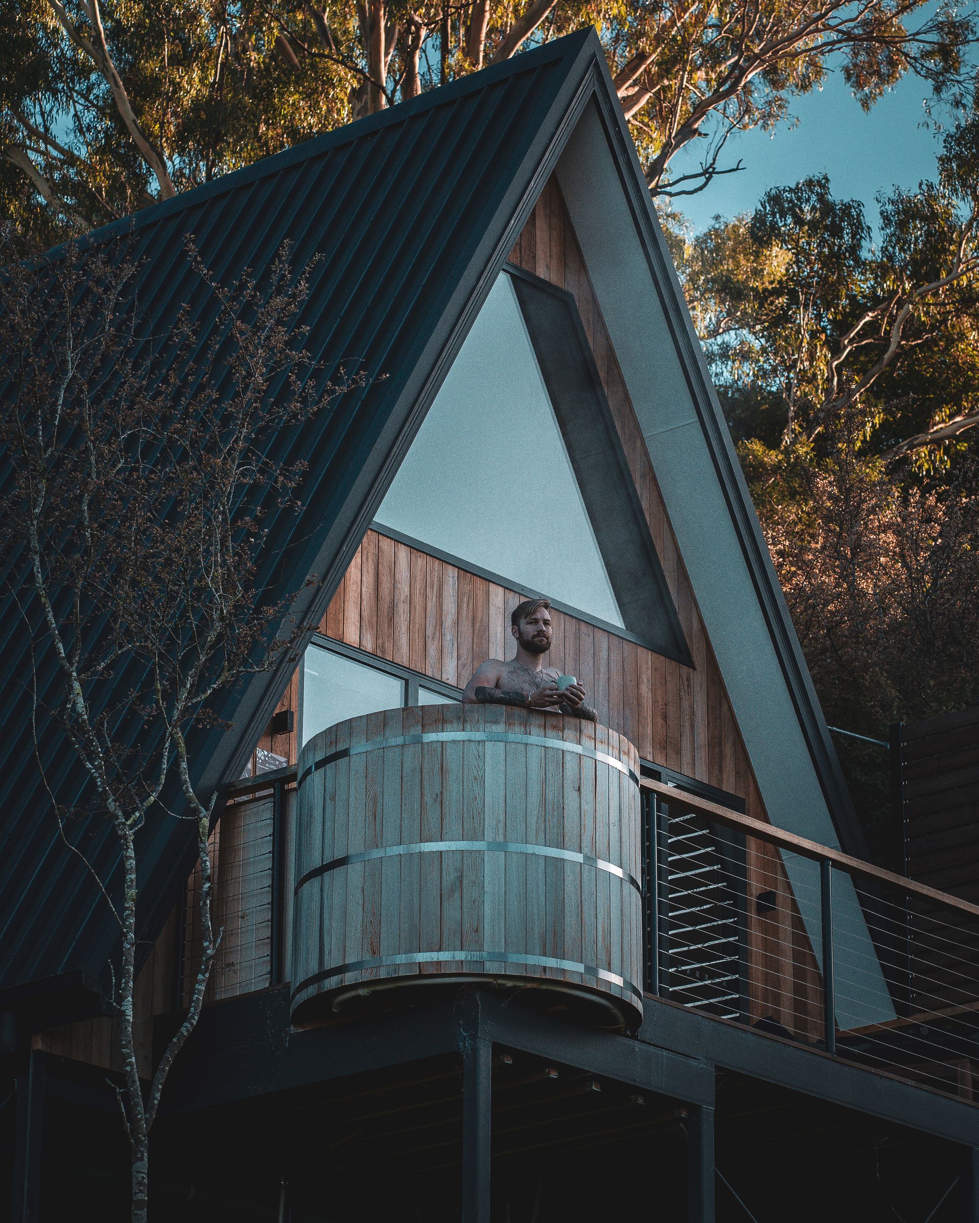The Eco Cabin Tasmania by Wild Life Environmental. Detailed view of cabin and guest enjoying hot tub