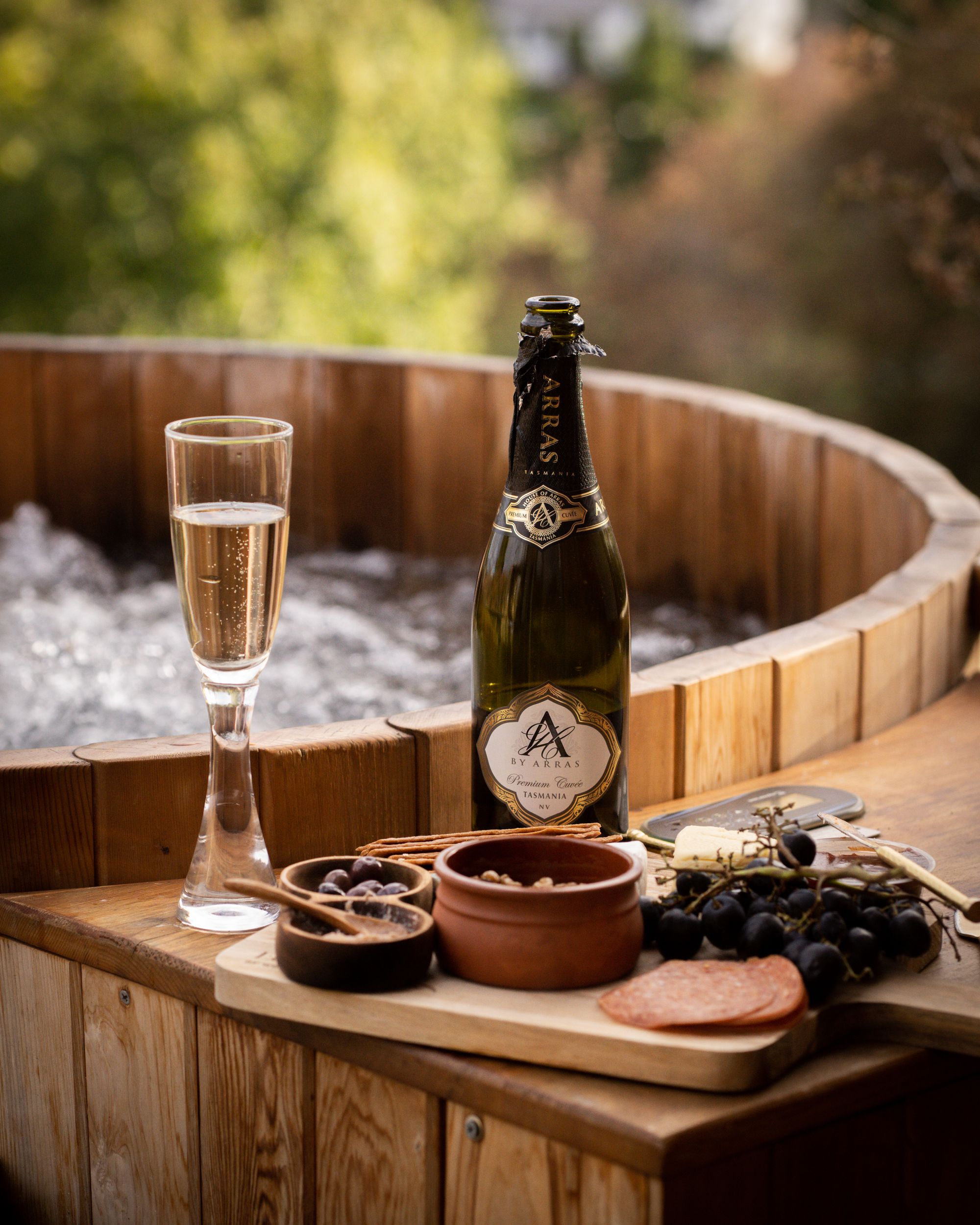 The Eco Cabin Tasmania by Wild Life Environmental.  Detailed view of hot tub and charcuterie board and champagne. 