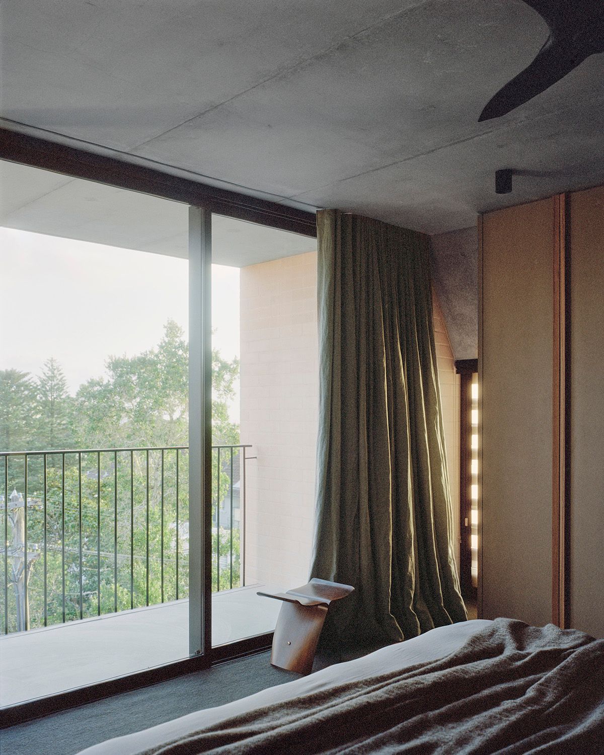 Bronte House by Tribe Studio Architects showing interior view of bedroom looking out large glass sliding doors to a private balcony