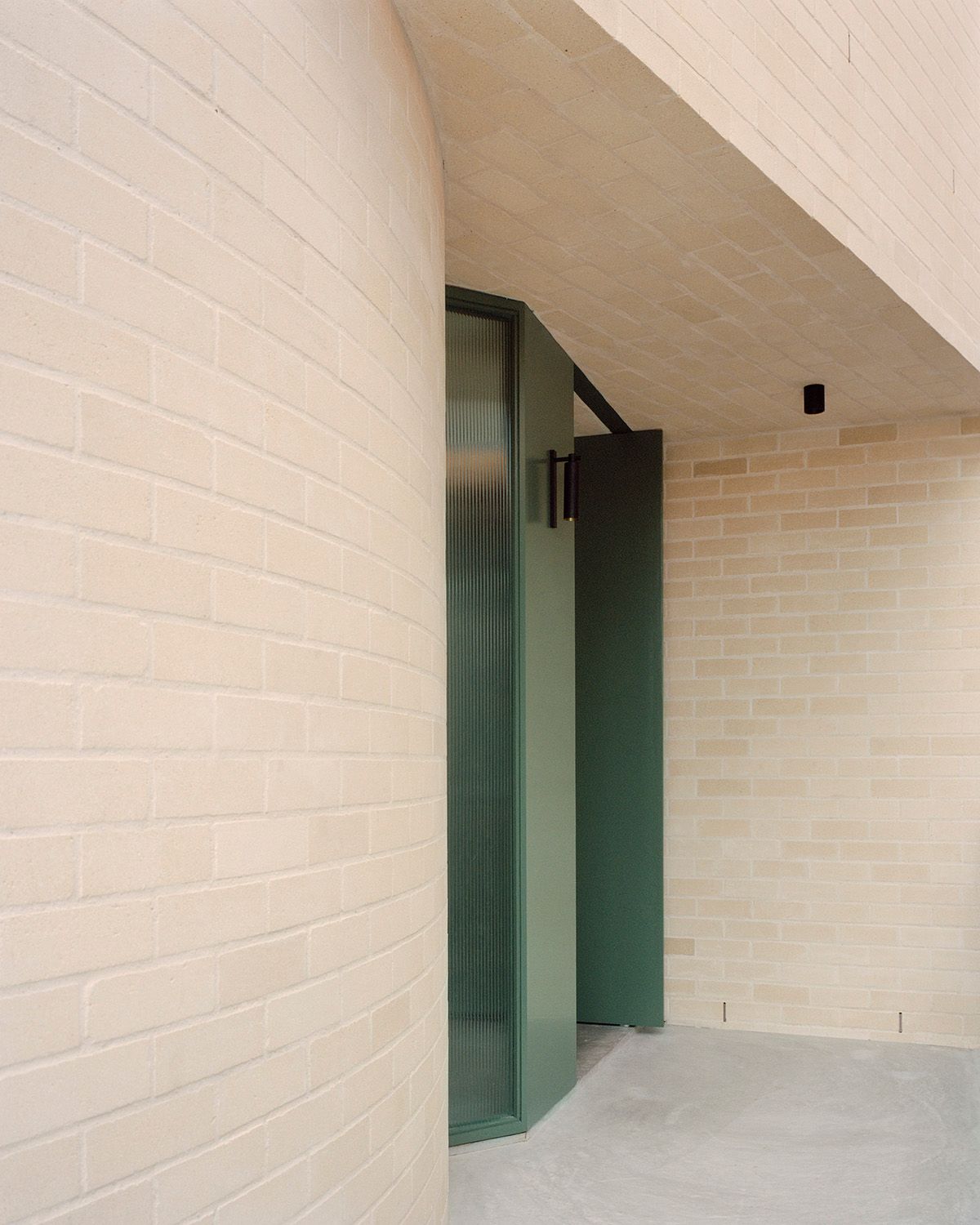Bronte House by Tribe Studio Architects showing green front entry door up against the cream brickwork