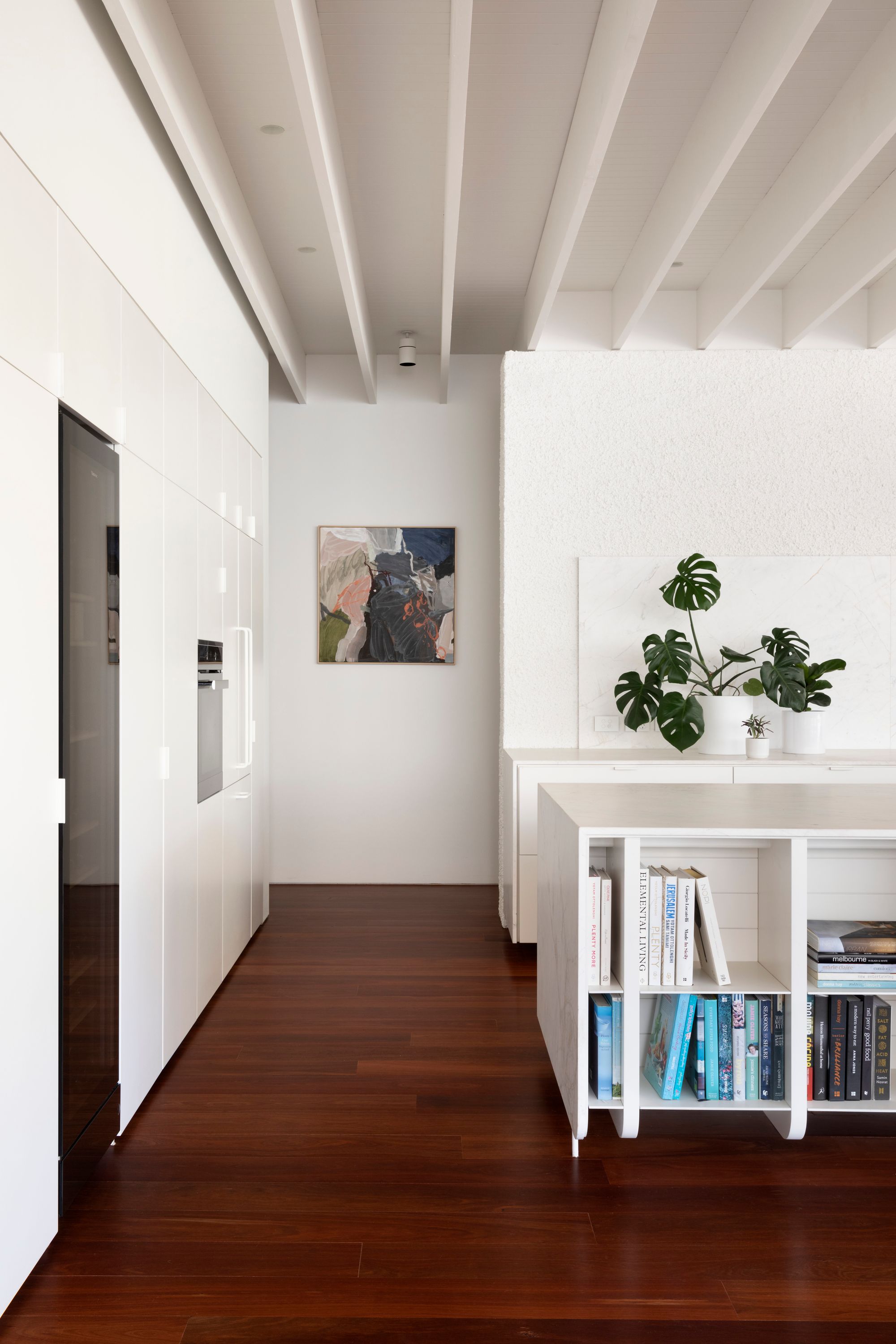 Elwood House by AM Architecture showing interior of kitchen space with white island bench and timber floors