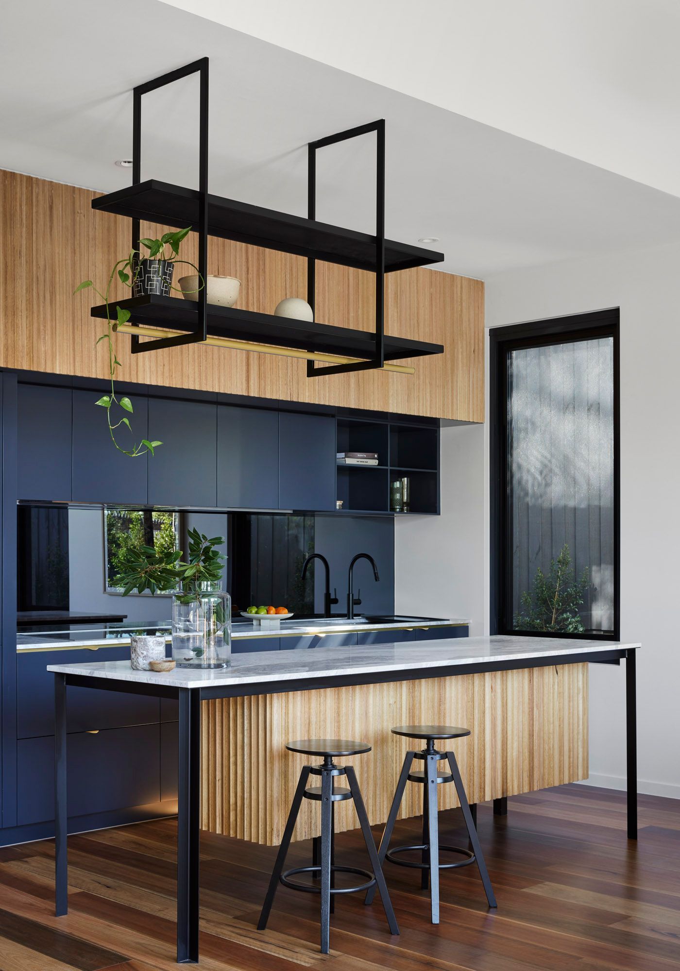 A kitchen island bench top with a variety of different materials: fluted Tasmanian timber, black steel and white marble