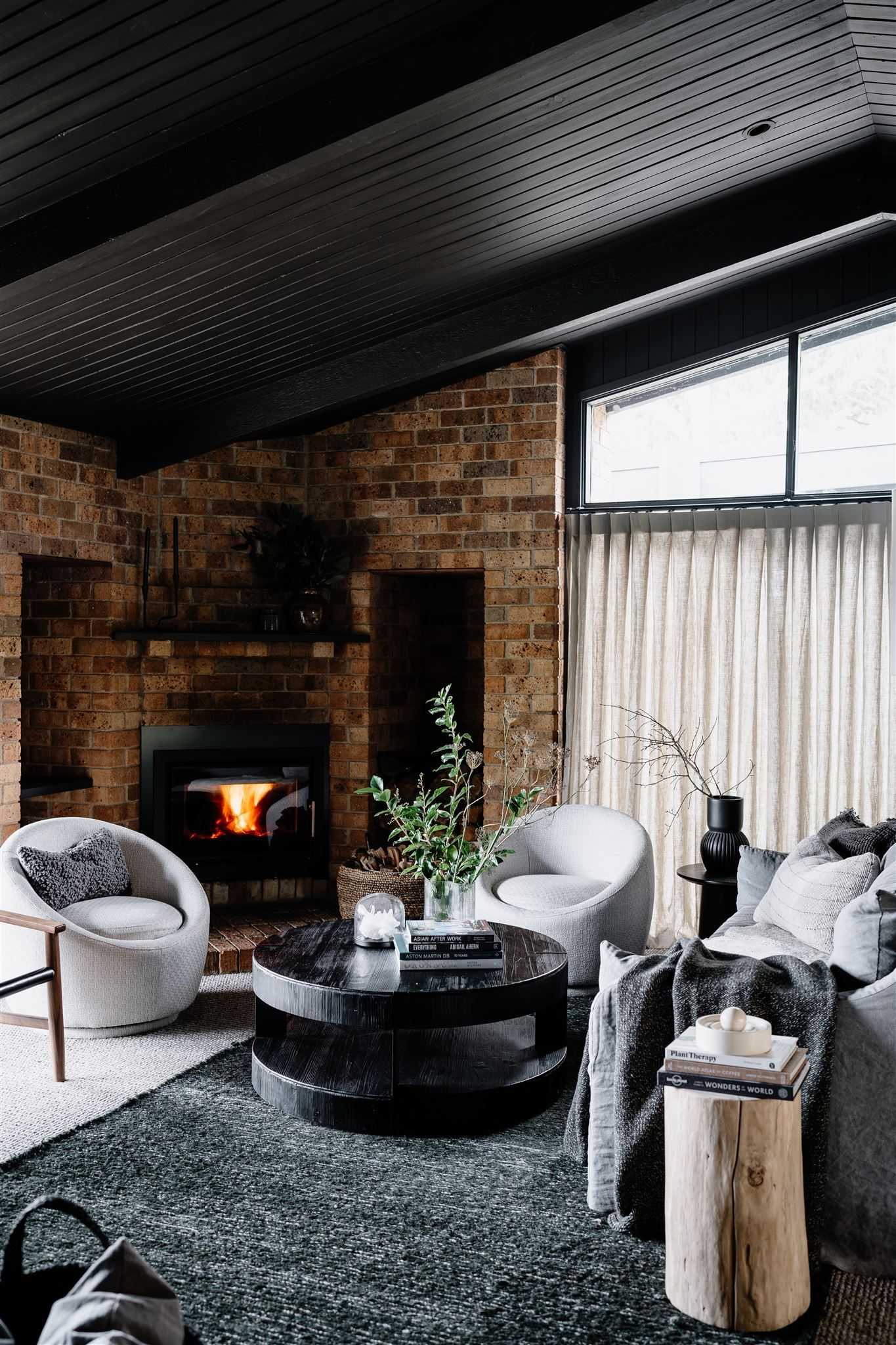Jumoku Daylesford. Showing the living room of the holiday home with a face brick wall and fireplace