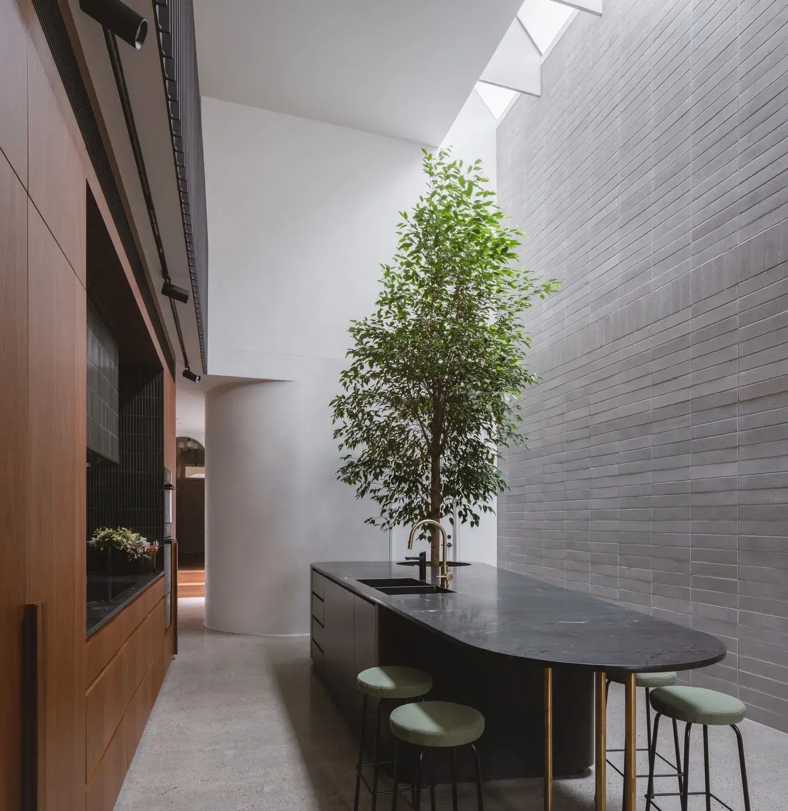 A large black stone kitchen island with a potted plant integrated into the design with a large tree