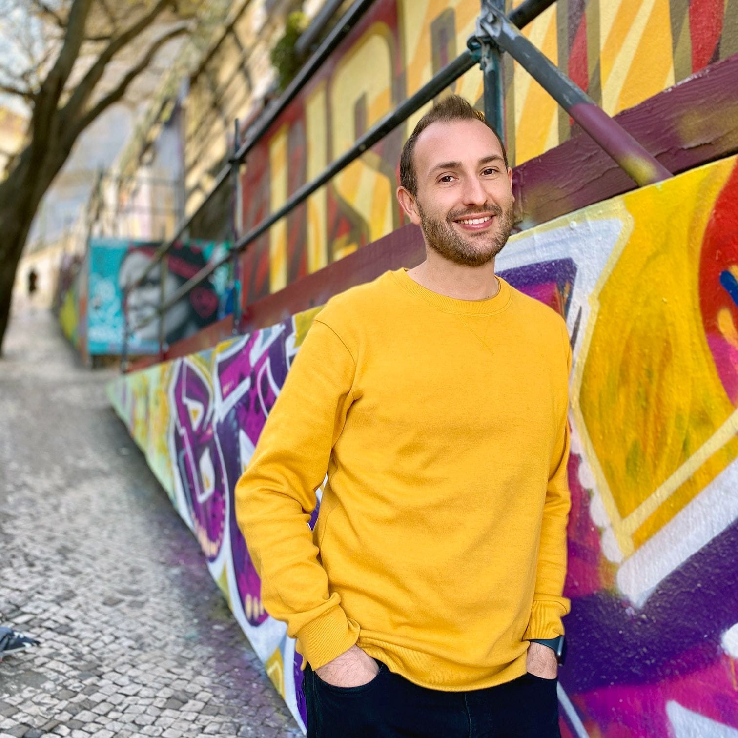 man standing in laneway with graffiti art and yellow sweater - Photo Credit: Decibel Architecture