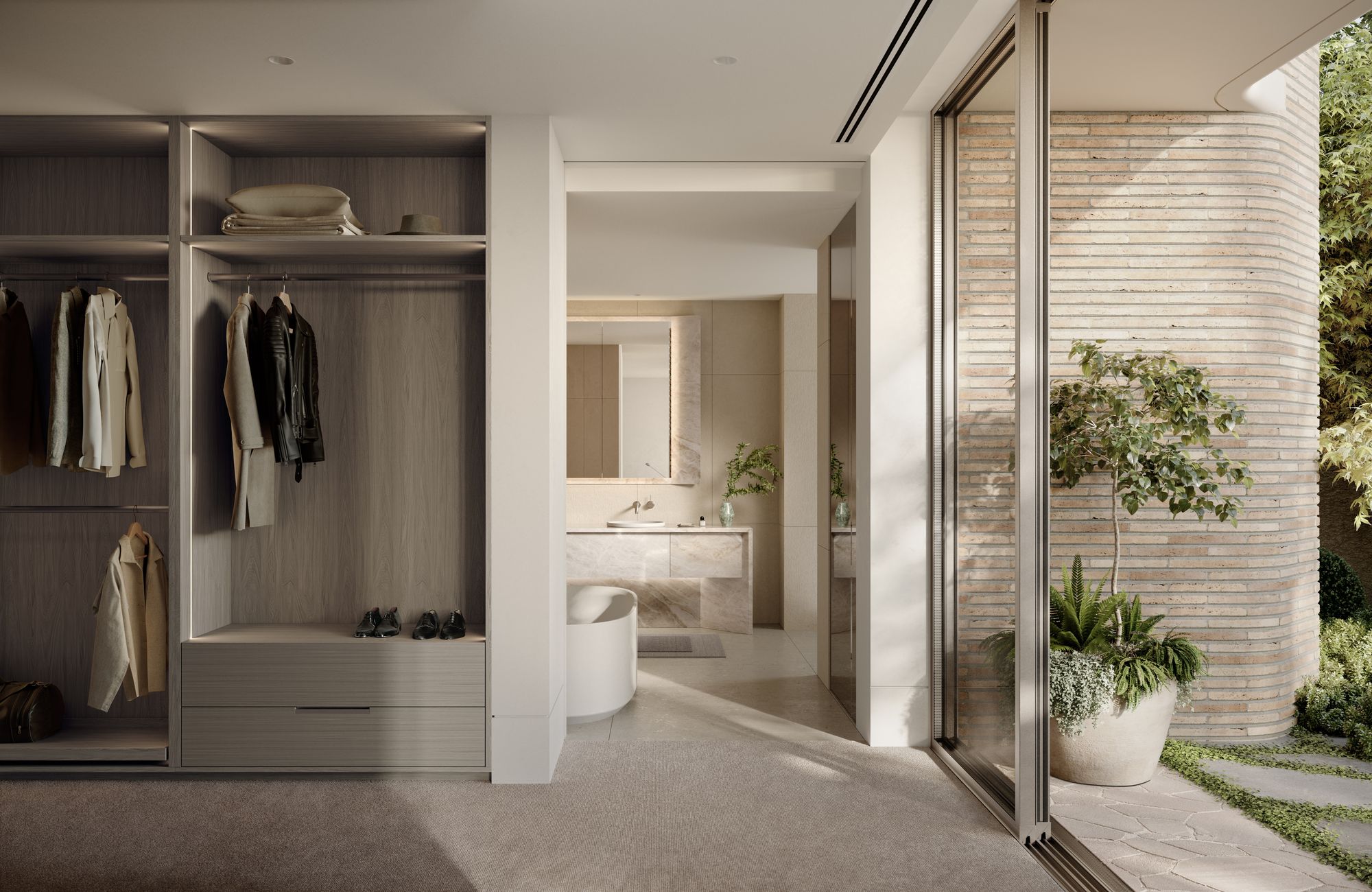 Como Toorak by Prime Edition x Jolson.The image displays an elegant interior space that seamlessly connects to an outdoor garden through large sliding glass doors. On the left, a built-in wardrobe with wood textures showcases neatly arranged clothing and accessories, exemplifying a clean and minimalist design. The view through the doorway reveals a sophisticated bathroom with a neutral color palette, enhancing the calm and luxurious atmosphere. Natural light floods the interior, blurring the lines between inside and outside, while the lush greenery visible through the glass adds a touch of nature to the urban home setting.