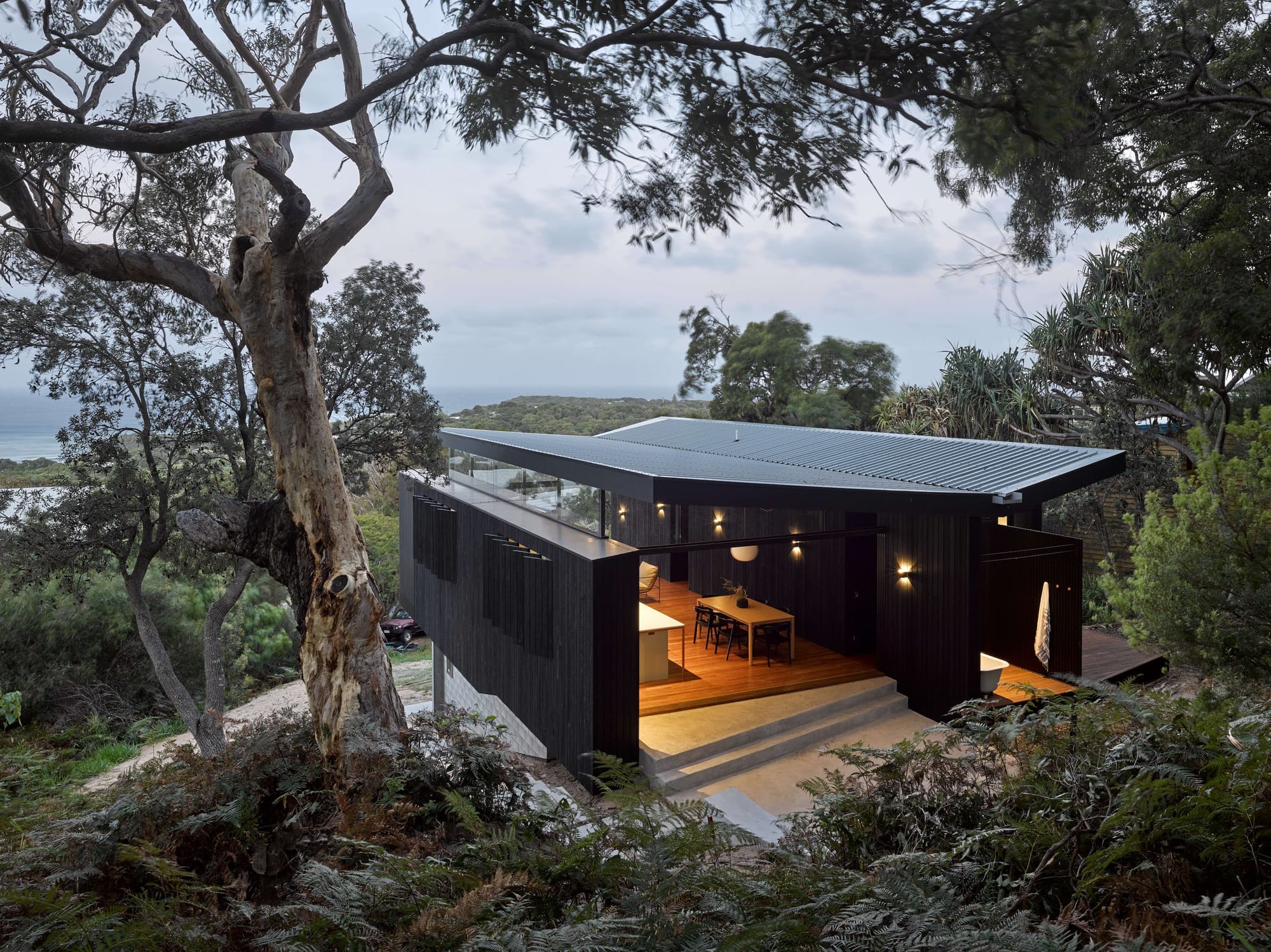 Baker Boys Beach House by REFRESH* Design Studio for Architecture showing dark cladding of tropical beach house overlooking water