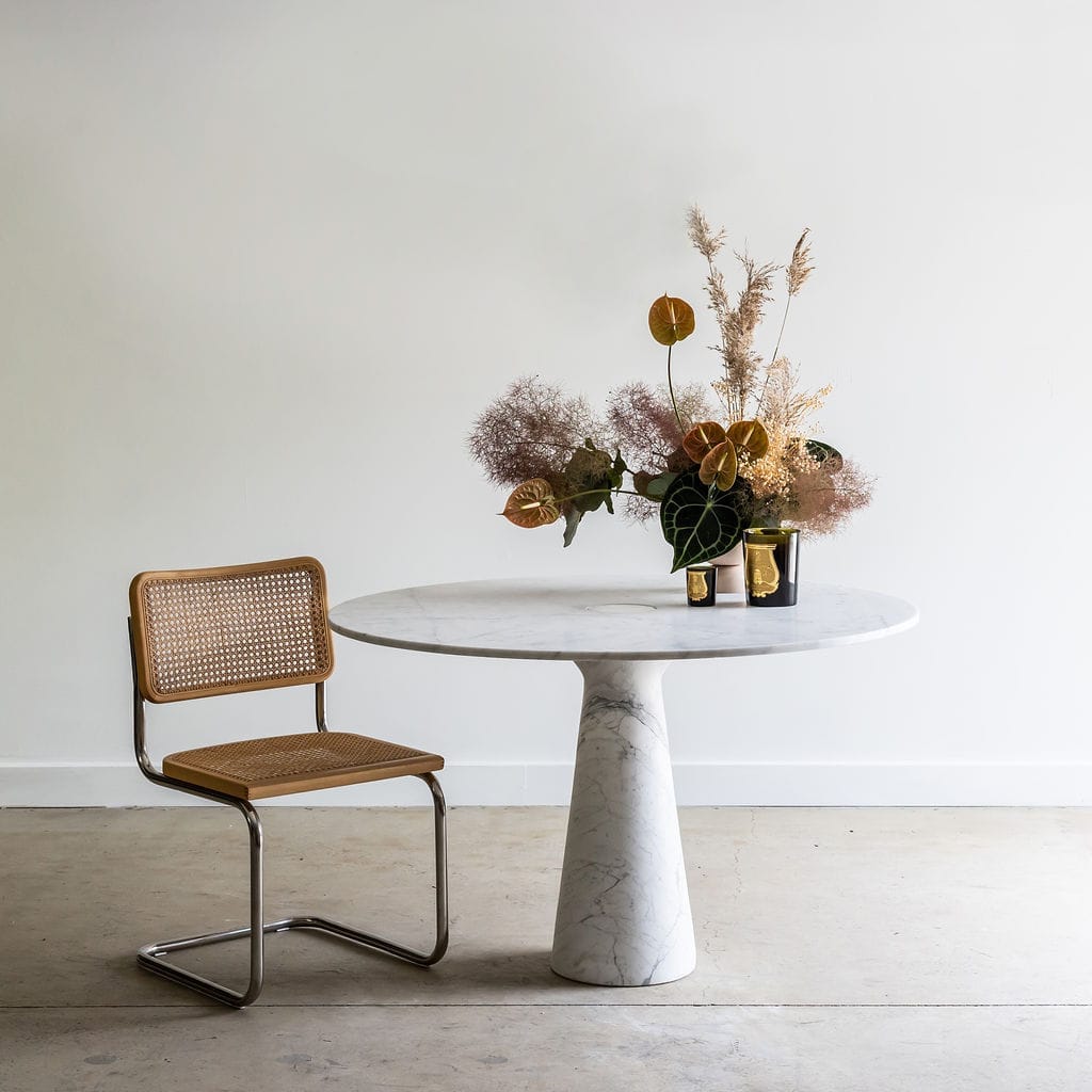 Noma Co Studio. Round marble table next to retro rattan chrome dining chair.
