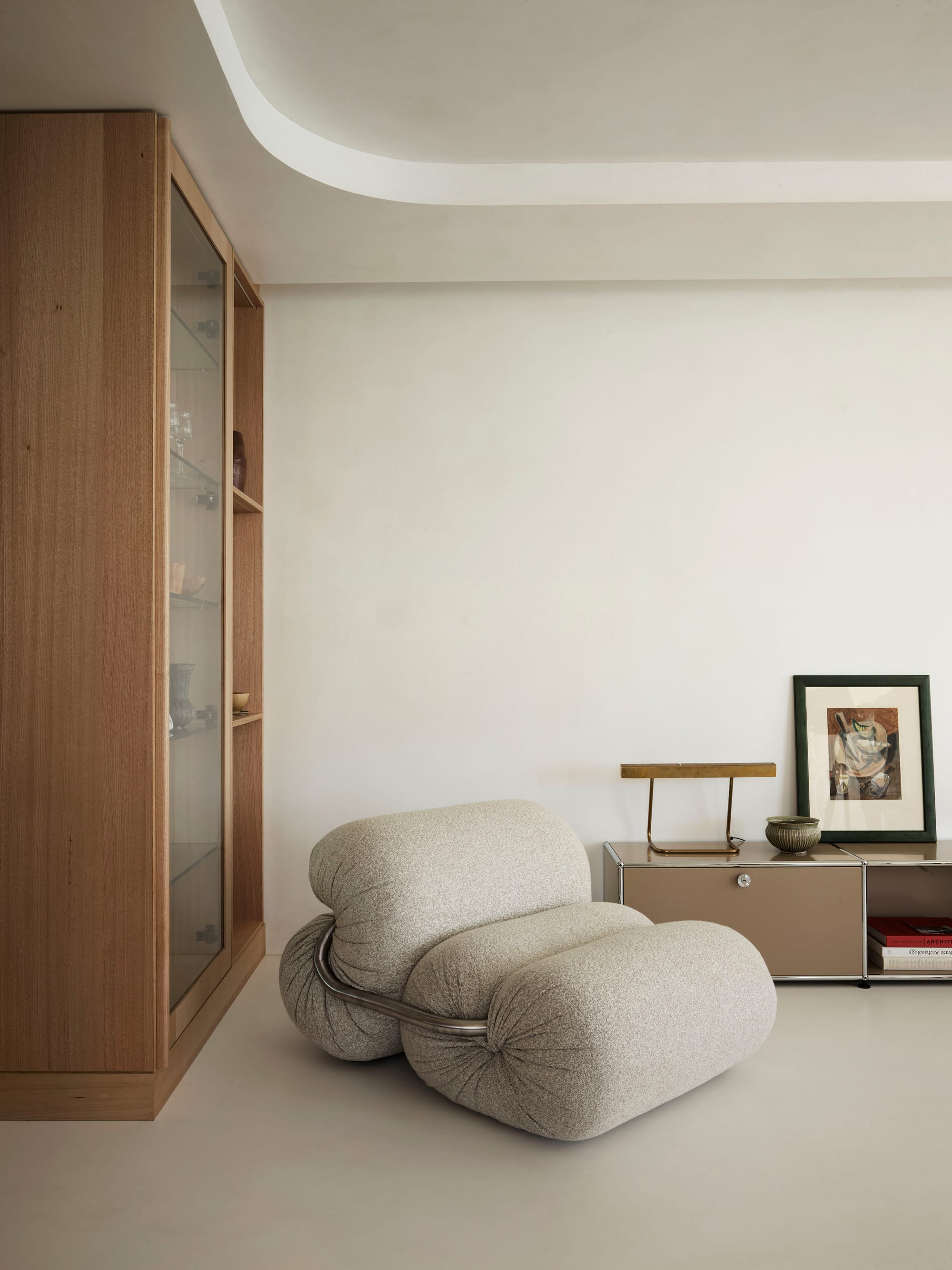 Tasmanian Timber Series: Darling Point Apartment. Photography by Ansen Smart. Vertical shot of neutral, boucle curved airmchair. White neutral floor and walls. Tasmanian Oak cabinetry on left hand side of image. 