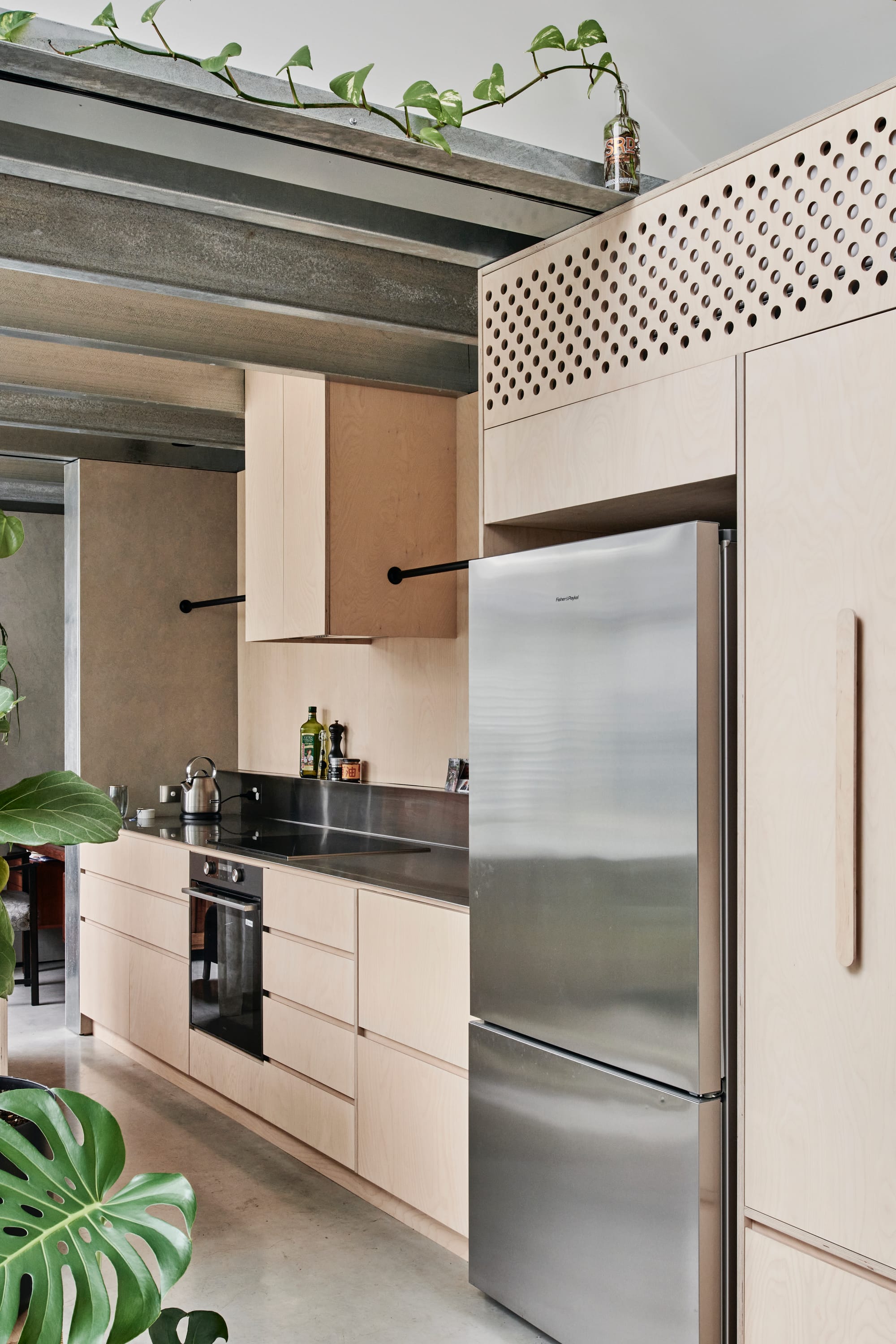 That Old Chestnut by FIGR. Architecture & Design. Photography by Tom Blachford. Galley style kitchen with concrete floors and plywood finished cabinetry. Steel appliances. Exposed steel beams across ceiling. 