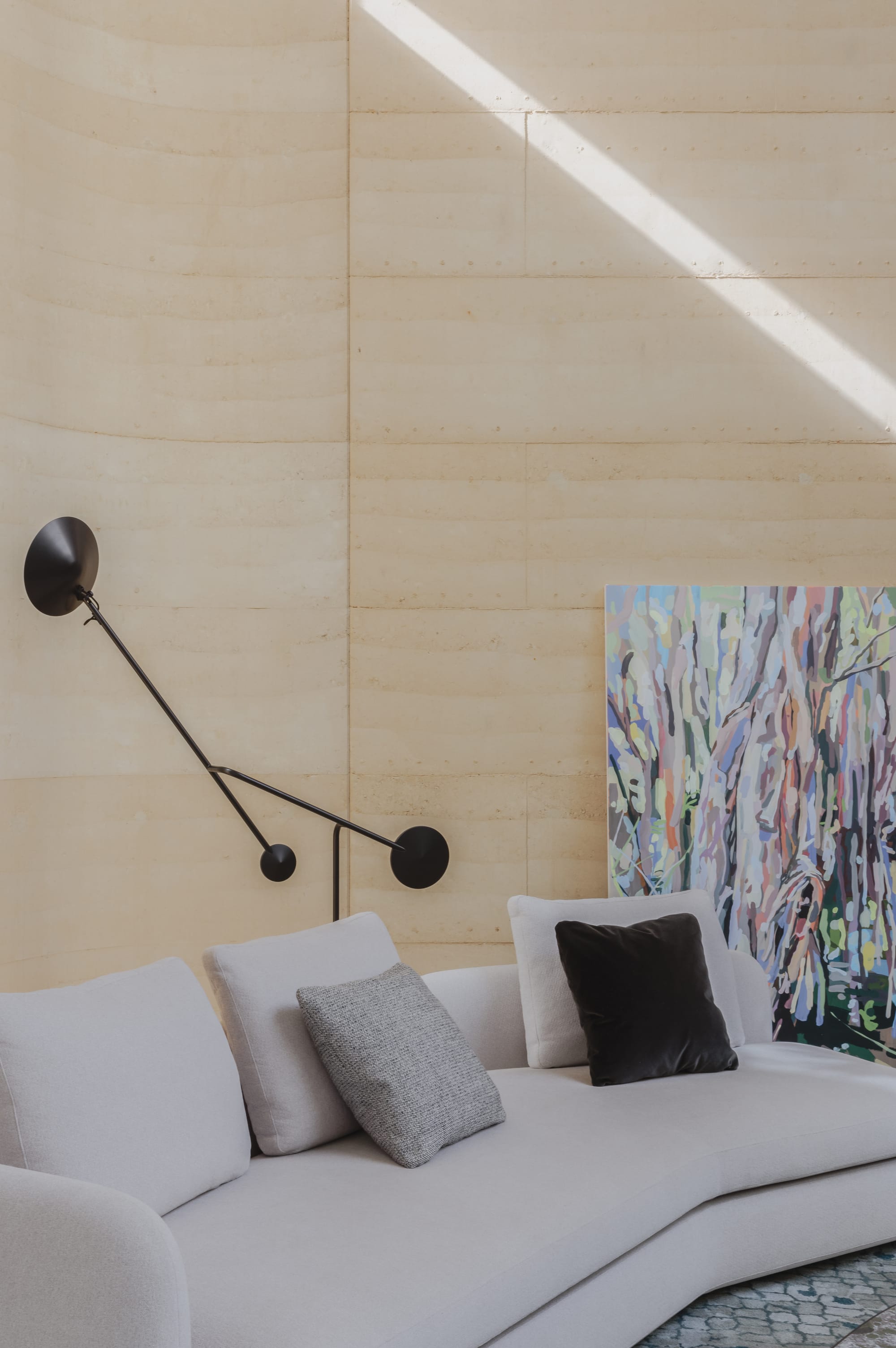 Kenneth Street by Design Studio Group showing the rammed earth wall in the living room and the sofa in the foreground