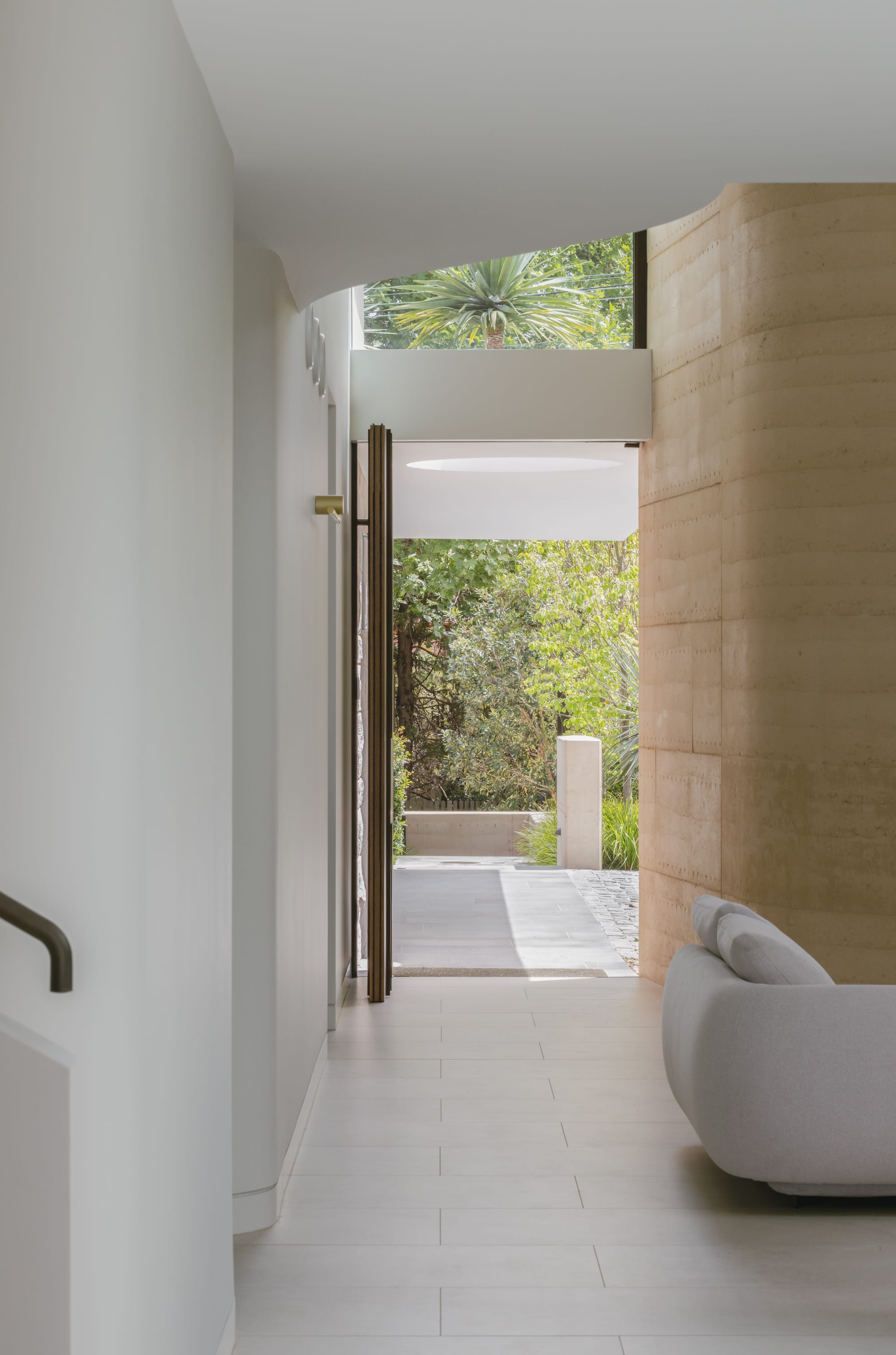 Kenneth Street by Design Studio Group showing the pivot front door open and the rammed earth wall at entry