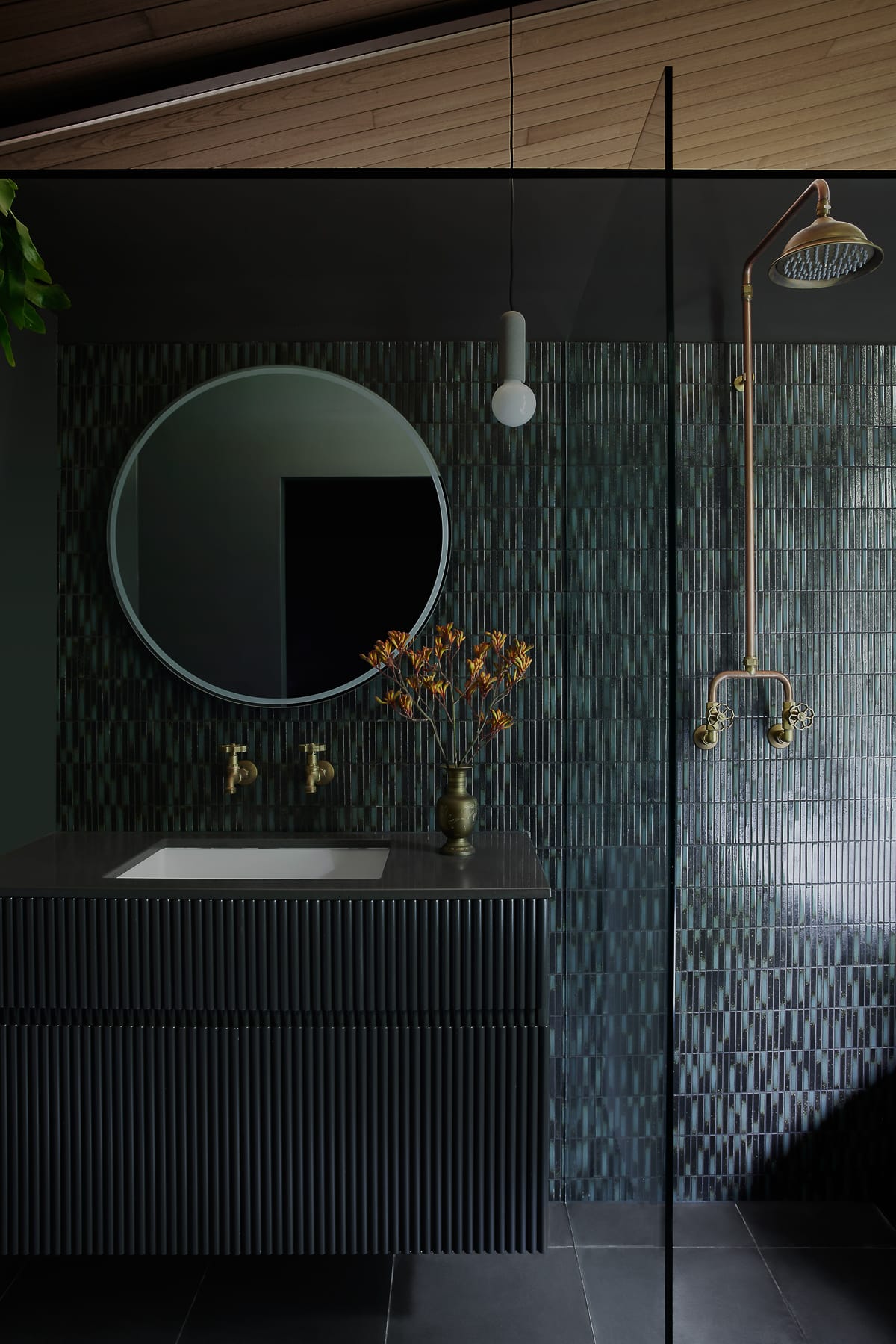 An interior shot of the blue tiled bathroom showing the dark vanity and brass tapware