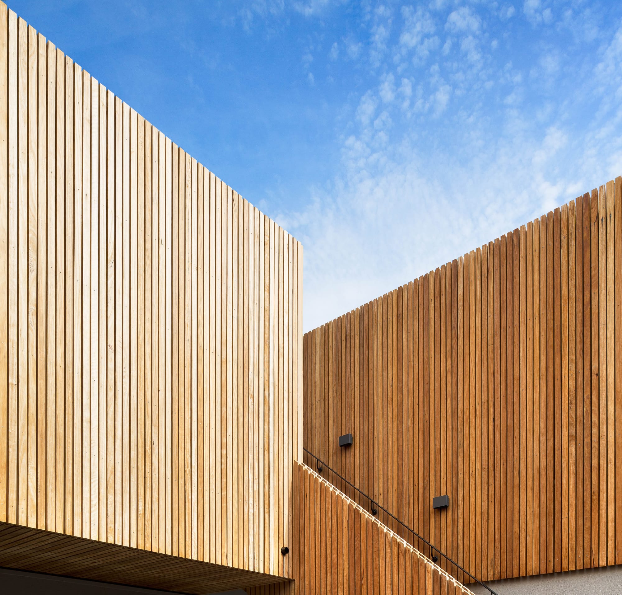 A detail shot of the external timber cladding and external staircase with blue sky behind
