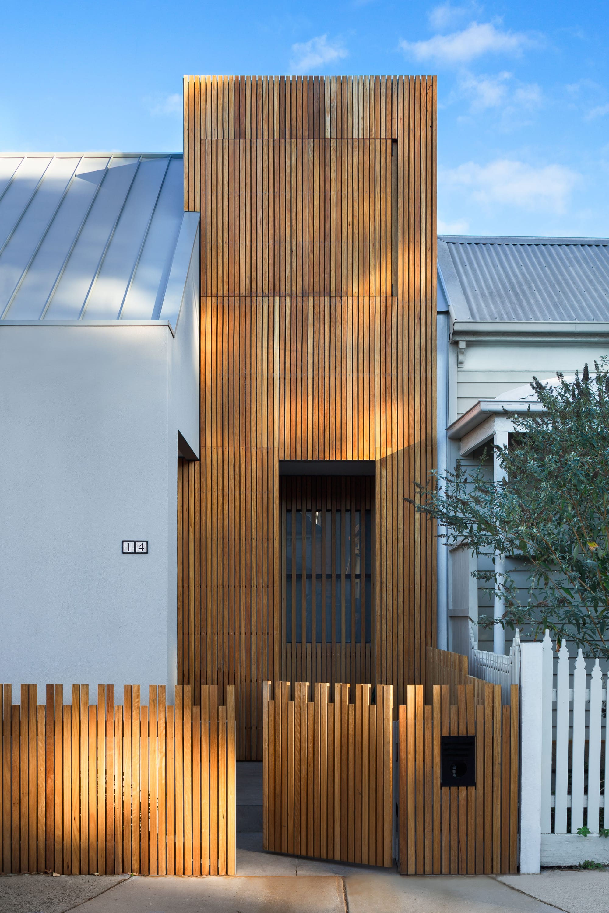 A shot from the street showing the renovated houses facade with timber and render and a timber front fence