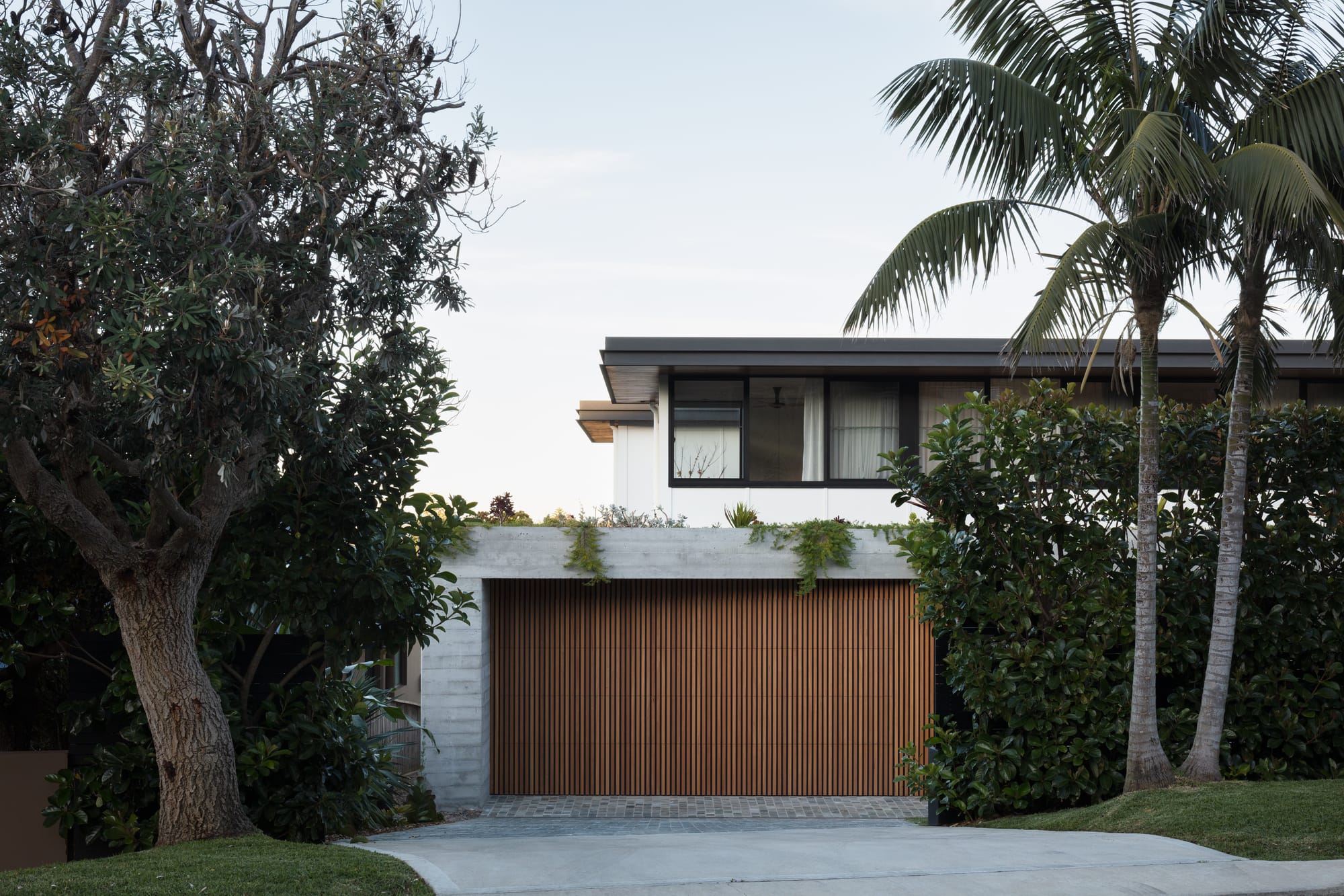 Grandview House by Ian Bennett Design Studio. Photography by Clinton Weaver. Streetview facade of contemporary, double storey home with concrete second floor and timber clad garage door. 
