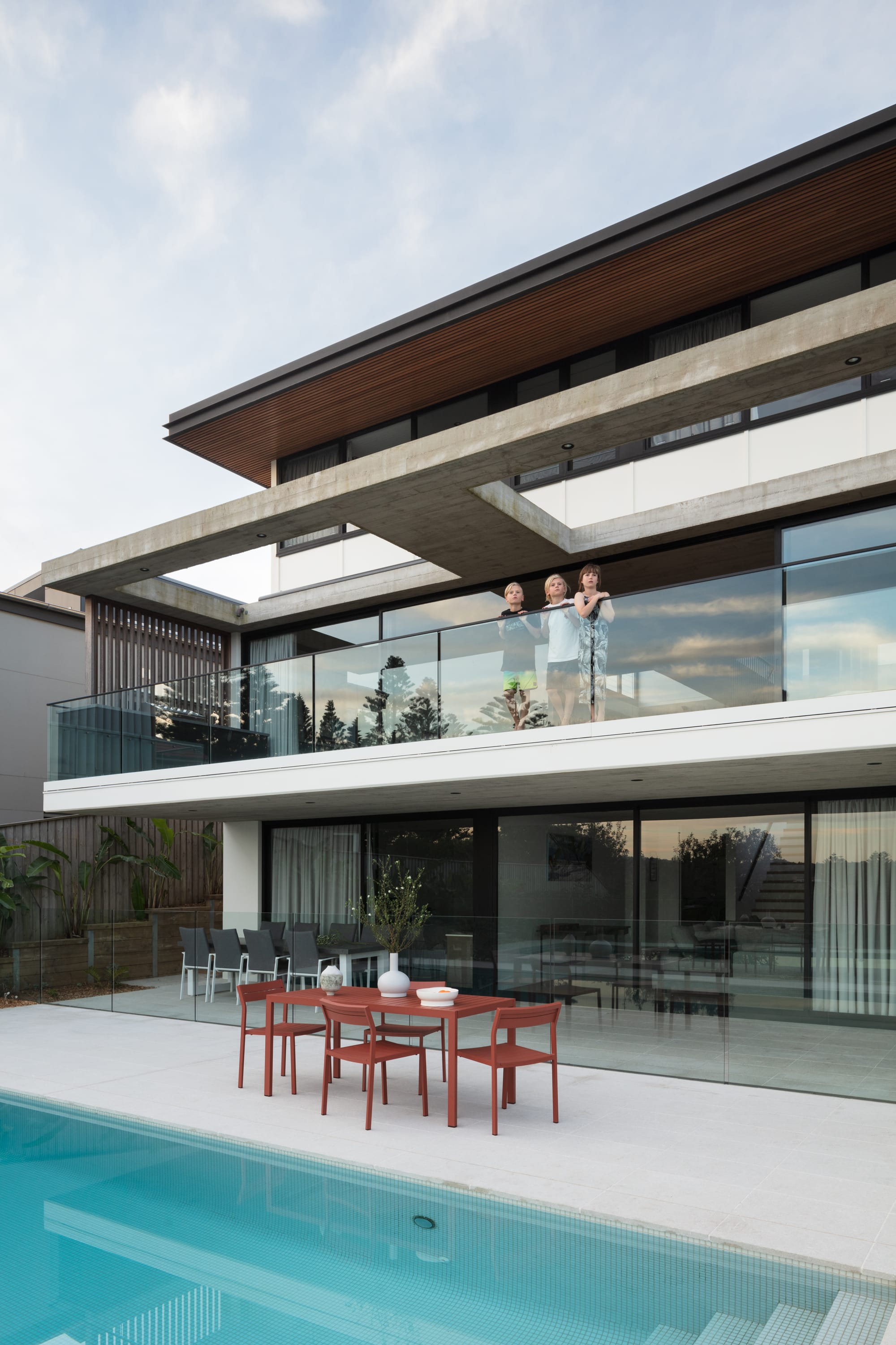 Grandview House by Ian Bennett Design Studio. Photography by Clinton Weaver. Rear facade of contemporary home with concrete balcony overlooking tiled pool. 