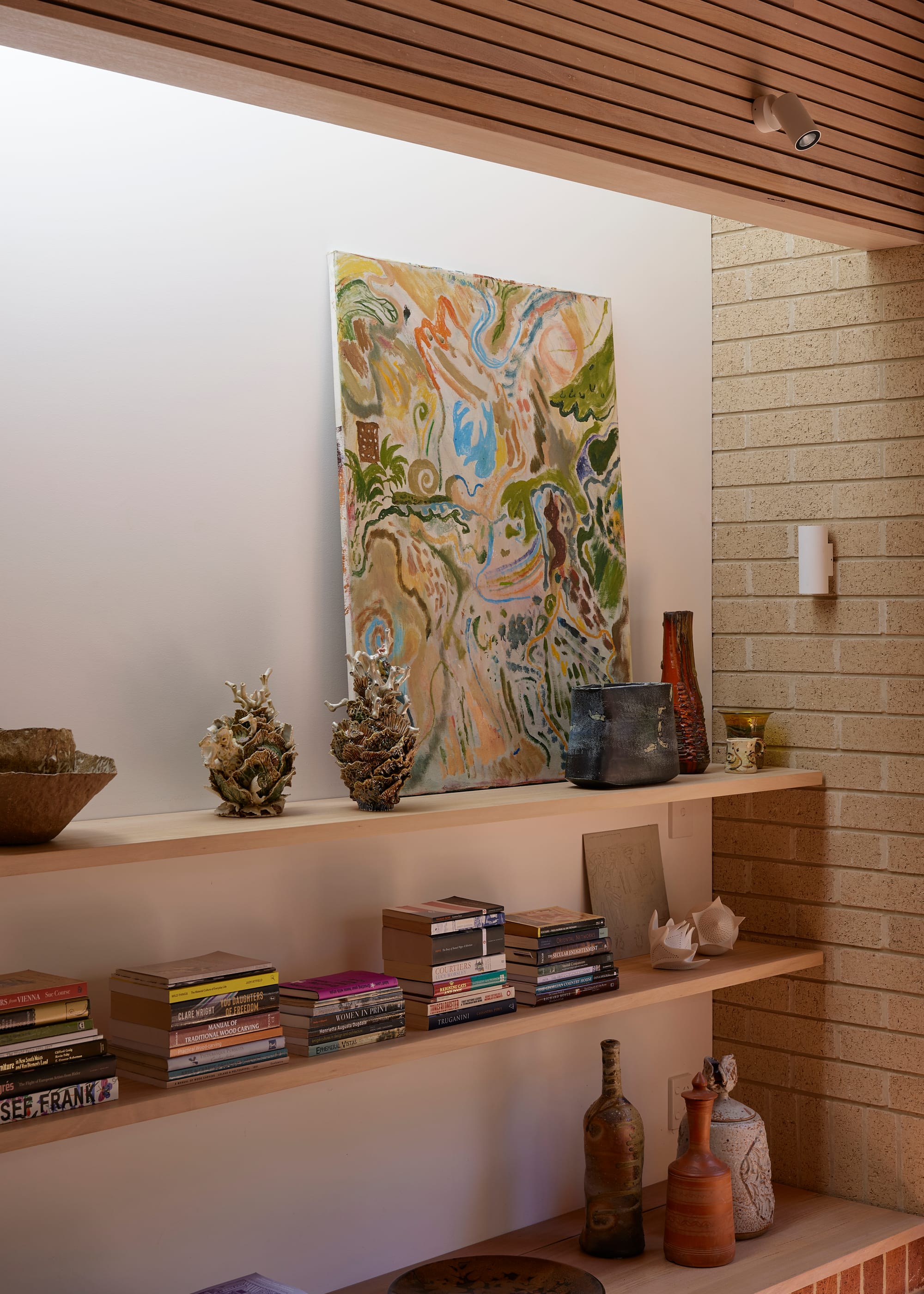 Harriet's House by SO:Architecture. Photography by Sean Fennessy. Floating oak shelves in front of brick wall. Abstract art and lots of books displayed.