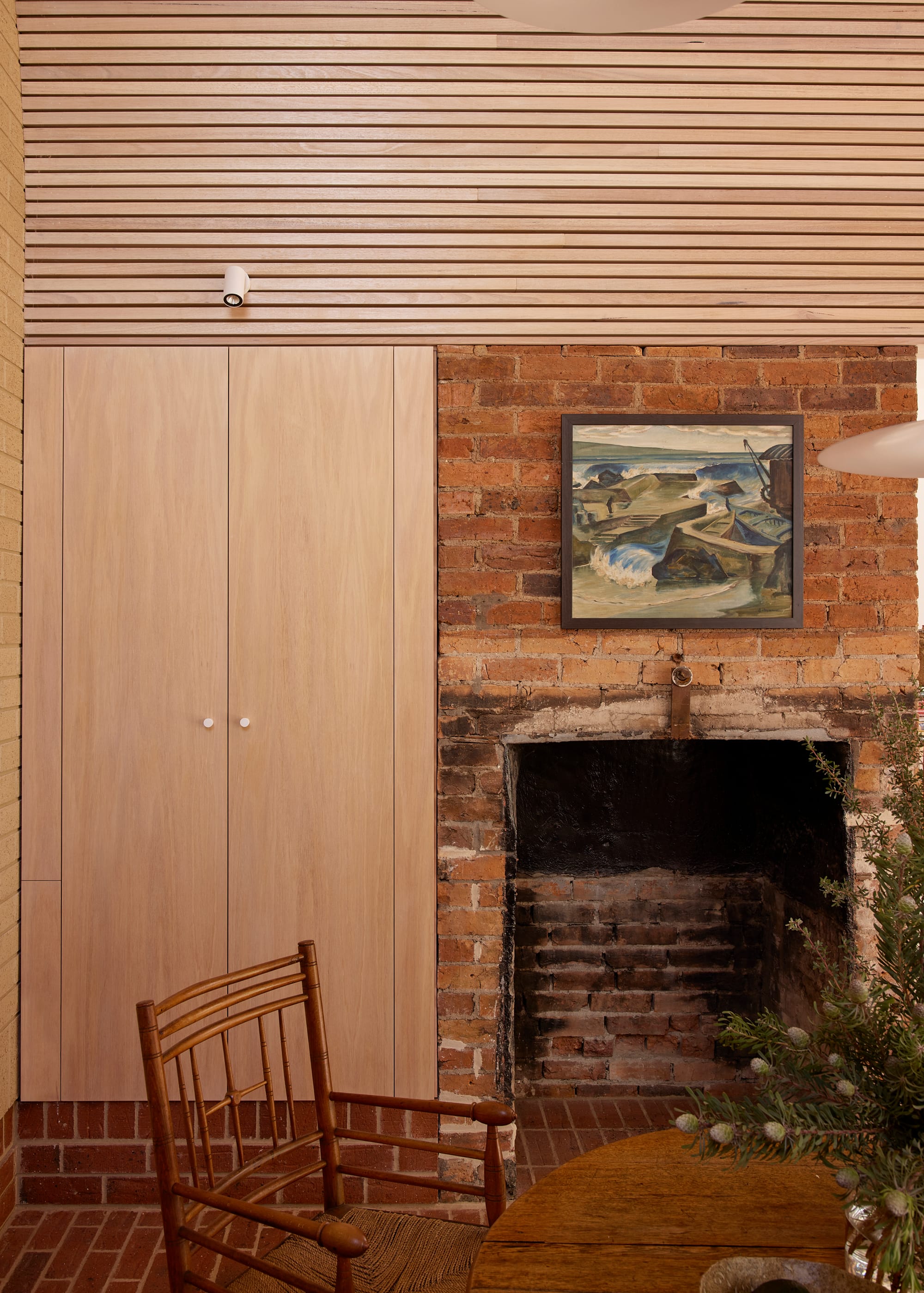 Harriet's House by SO:Architecture. Photography by Sean Fennessy. Brick fireplace behind heritage dining table and chair. Tasmanian Oak cupboard to left and clad above.