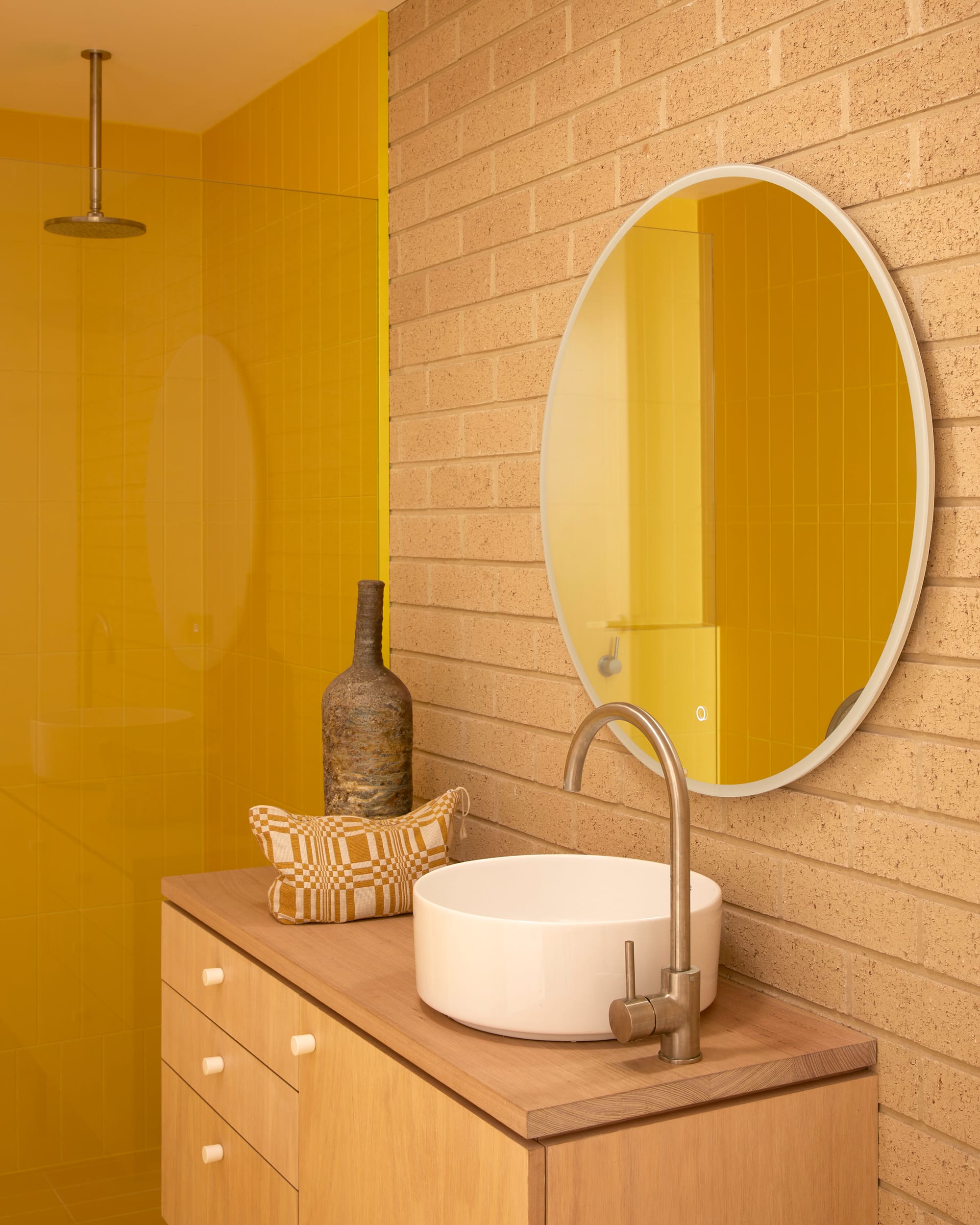 Harriet's House by SO:Architecture. Photography by Sean Fennessy. Bathroom with bright yellow tiles in shower. Pale brick walls. Tasmanian Oak counter and benchtop with round white sink.