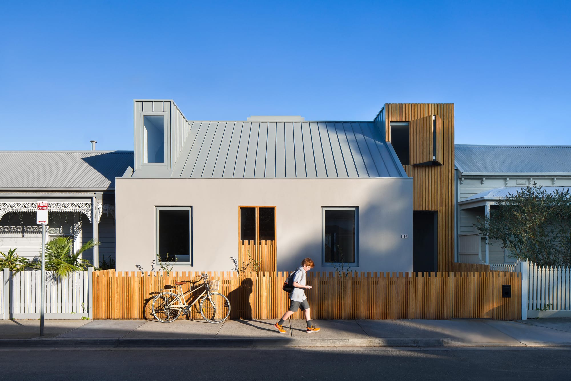  Cremorne House by Trethowan. Photography by Emily Bartlett. Residential home with simple facade. Timber batten fence and second story structure to the left. 