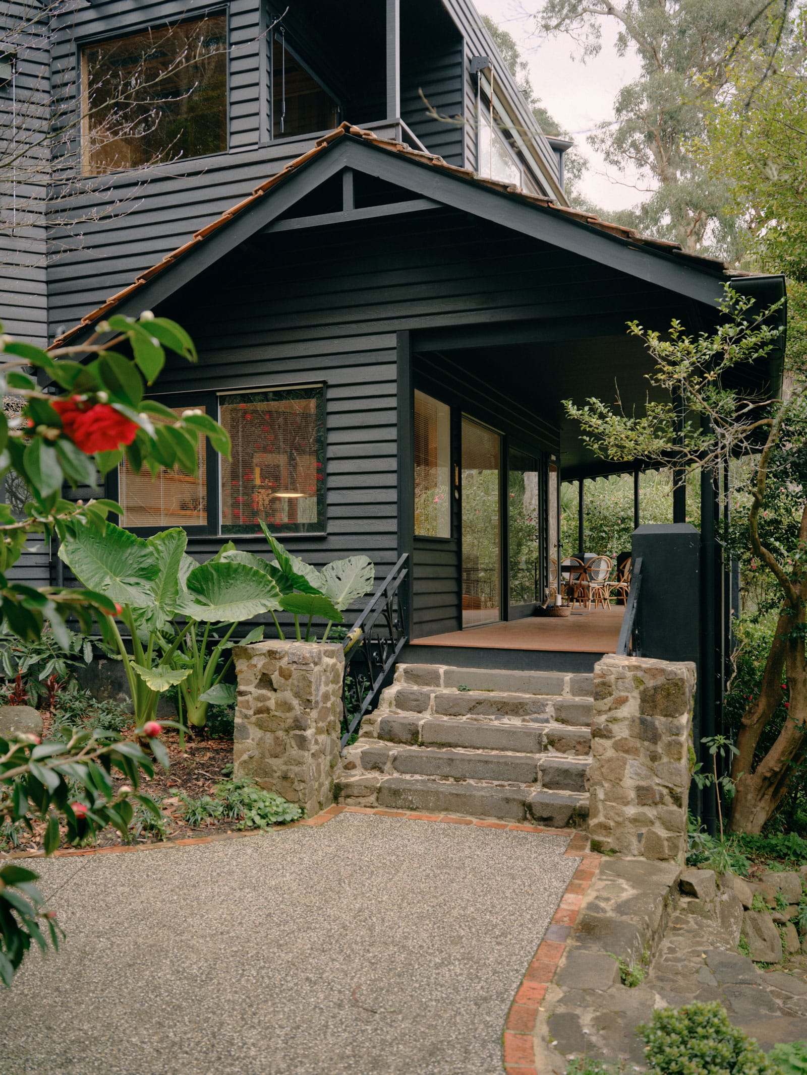  Selby House by Placement. Photography by Tom Ross. Exterior residential double storey home. Finished with black cladding, Stone steps leading to verandah. 