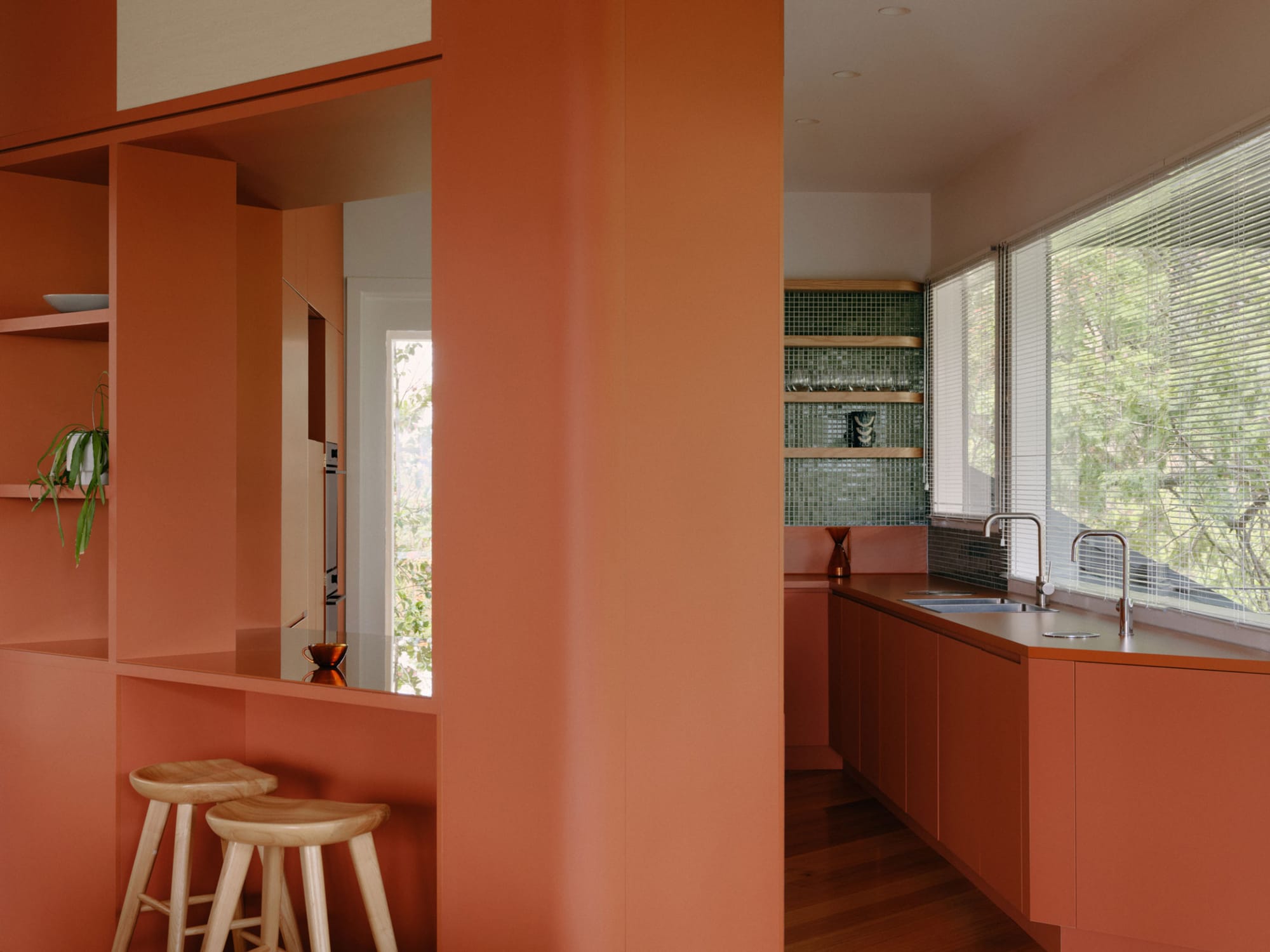 Selby House by Placement. Photography by Tom Ross. Residential kitchen with clay-coloured cabinetry and partition walls. Timber floors. Bottle green splashback tile.
