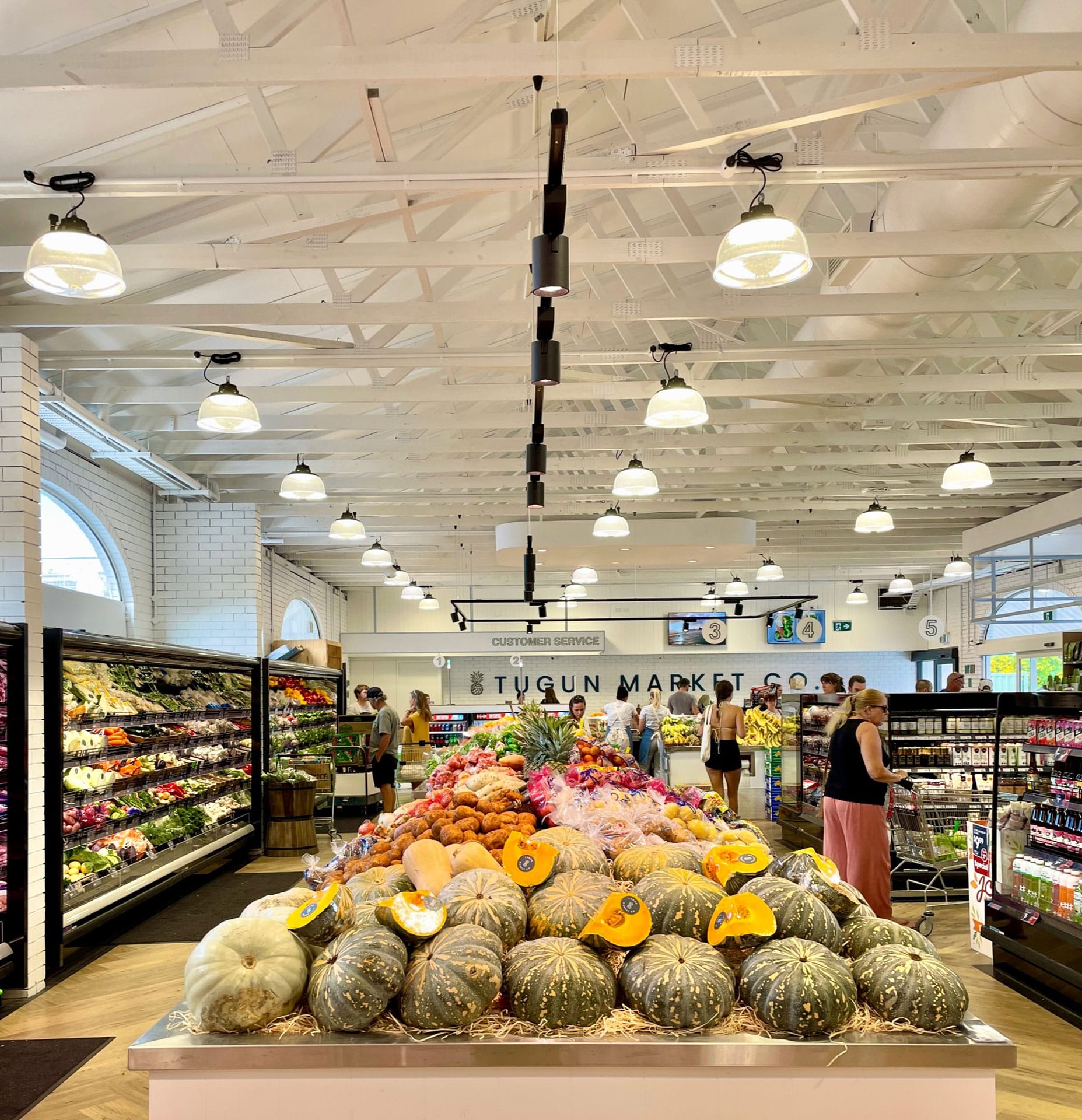 Tugun Market Co. by 77 Architecture. Photography by Brock Beazley. Interior of retail premise. Shelves of food arranged on right and left hand side of image. 