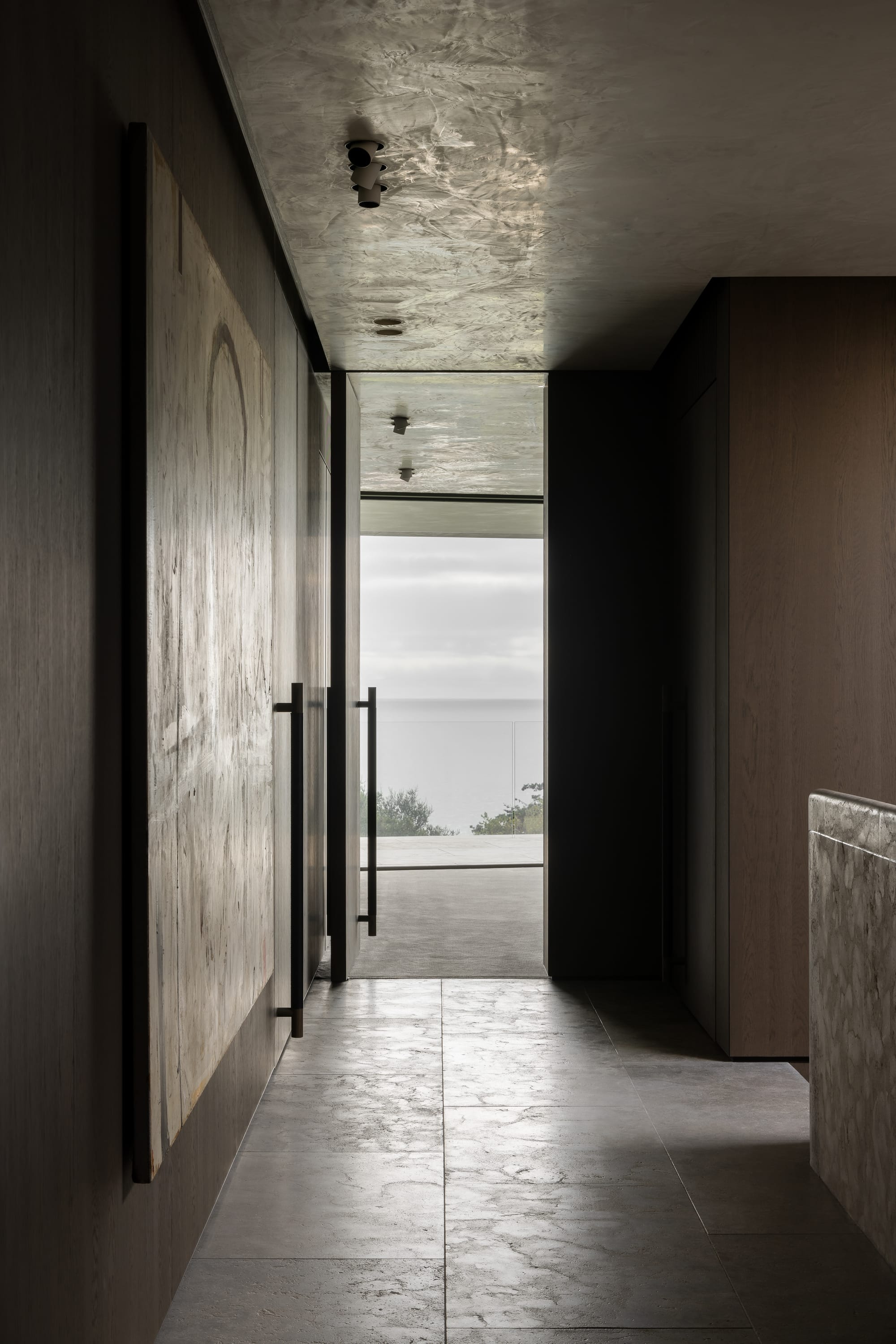 Cliff House by Finnis Architects. Photography by Timothy Kaye. Hallway on second storey showing ocean views. Stone floors and timber veneer walls.