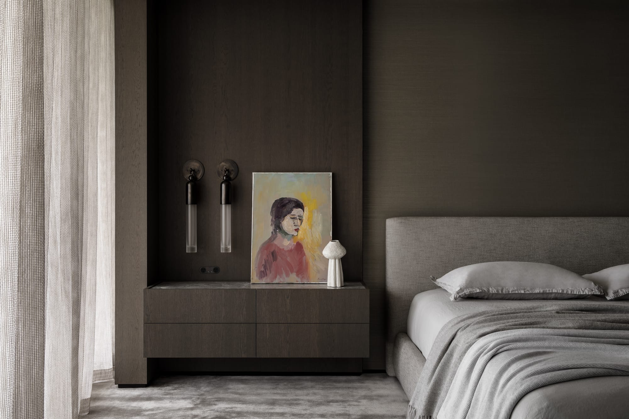 Cliff House by Finnis Architects. Photography by Timothy Kaye. Bedroom with grey flooring, timber veneer wall and olive wallpaper. Bed with neutral bedding and abstract painting on bedside counter. 