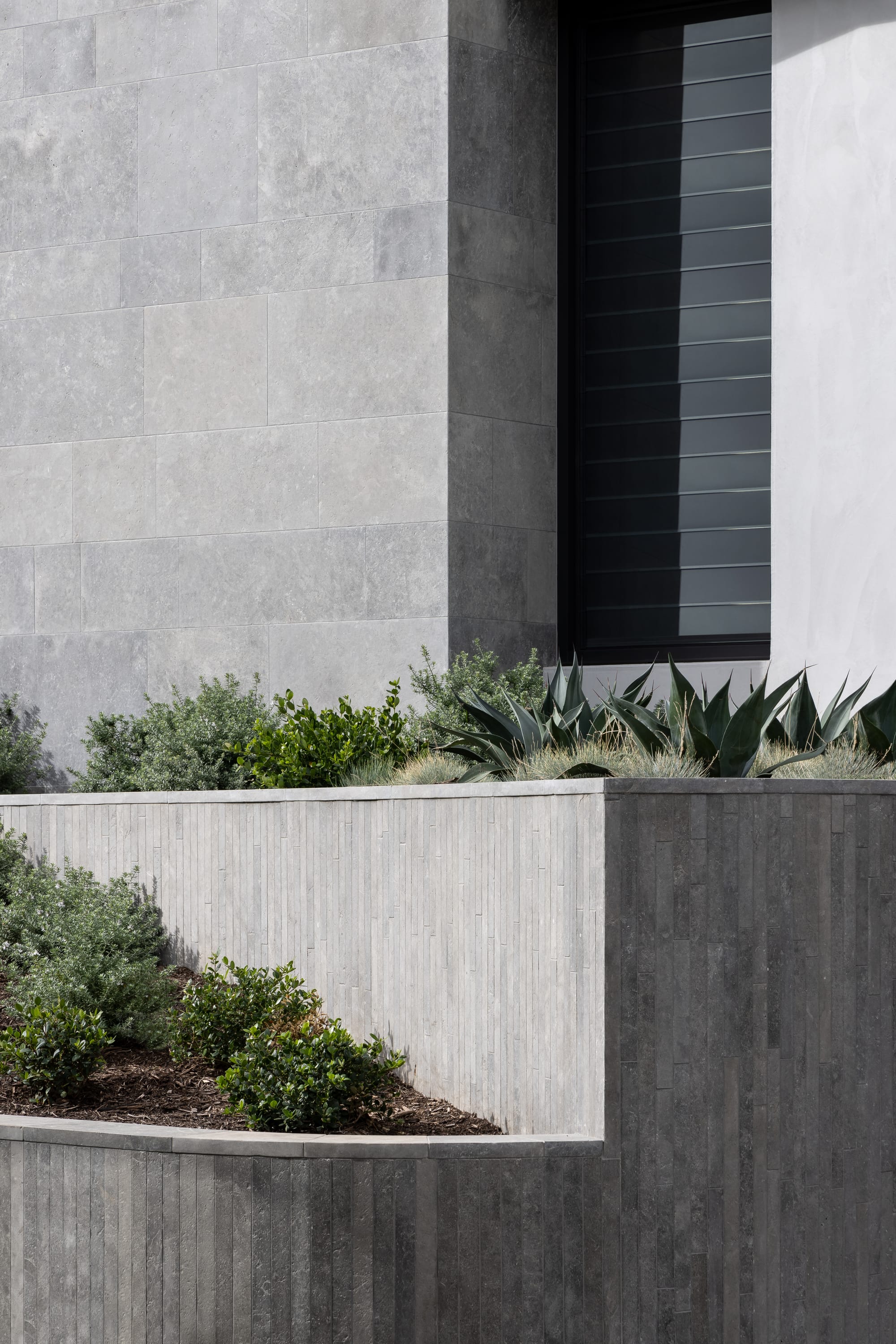 Cliff House by Finnis Architects. Photography by Timothy Kaye. Exterior of home with concrete finish. Integrated tiered garden beds and window with louvres. 