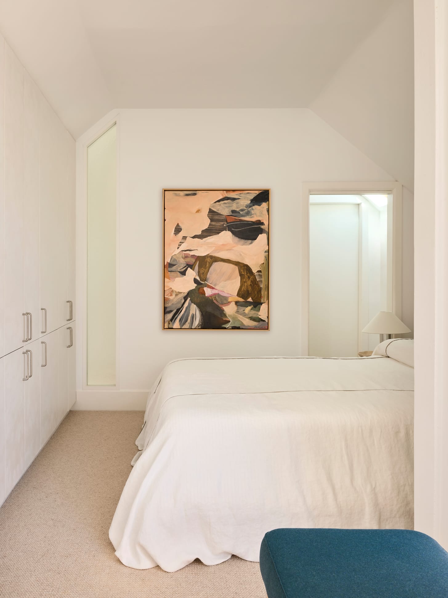Chapel House by FURNISHD. Photography by Alicia Taylor. Bedroom with beige carpets, white walls and cabinetry. White bed spread. Abstract art. 