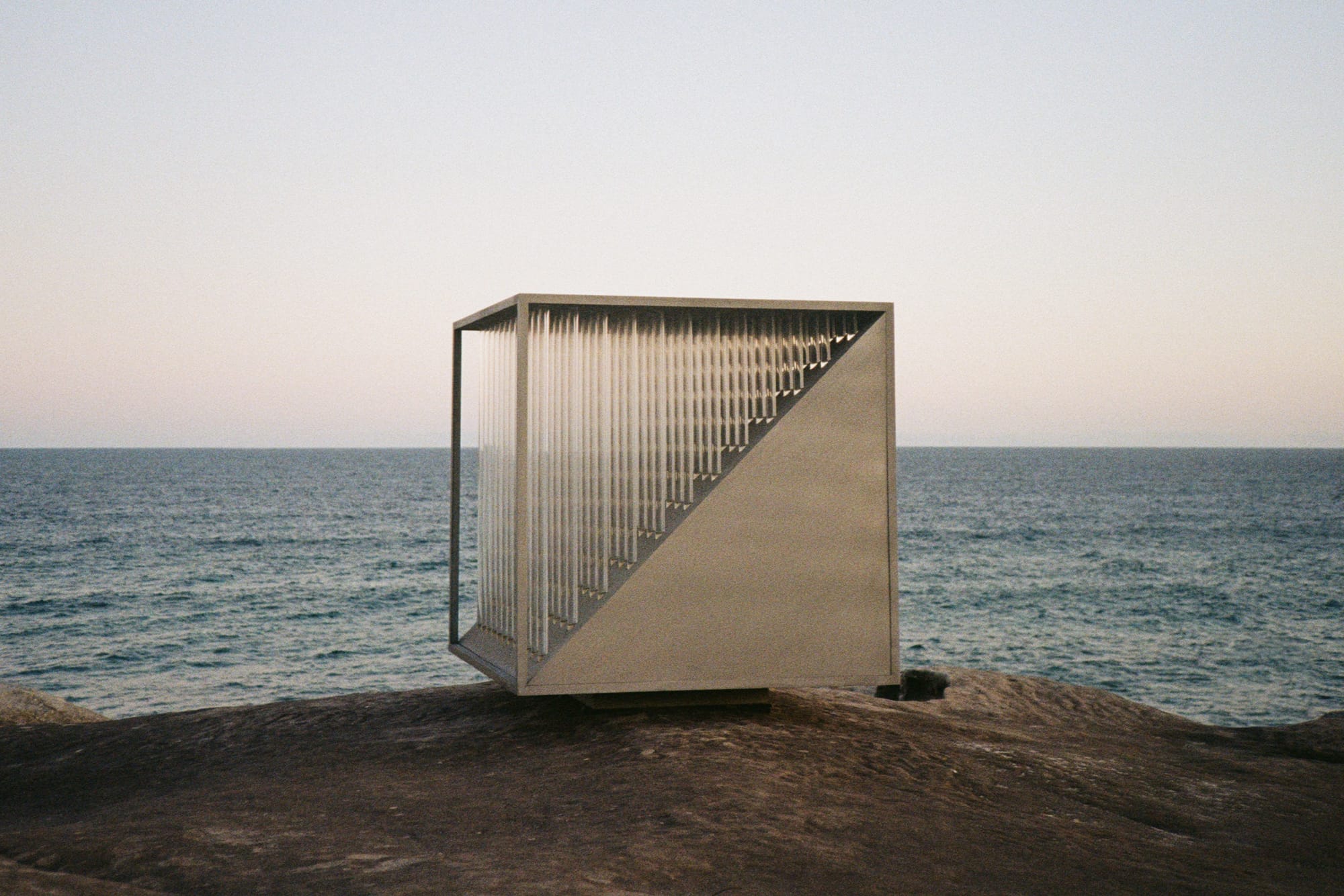 Array 8 by Studio Shand. Photography by Benjamin Jay Shand. Metal abstract 3D cube sculpture on rock cliff overlooking ocean.