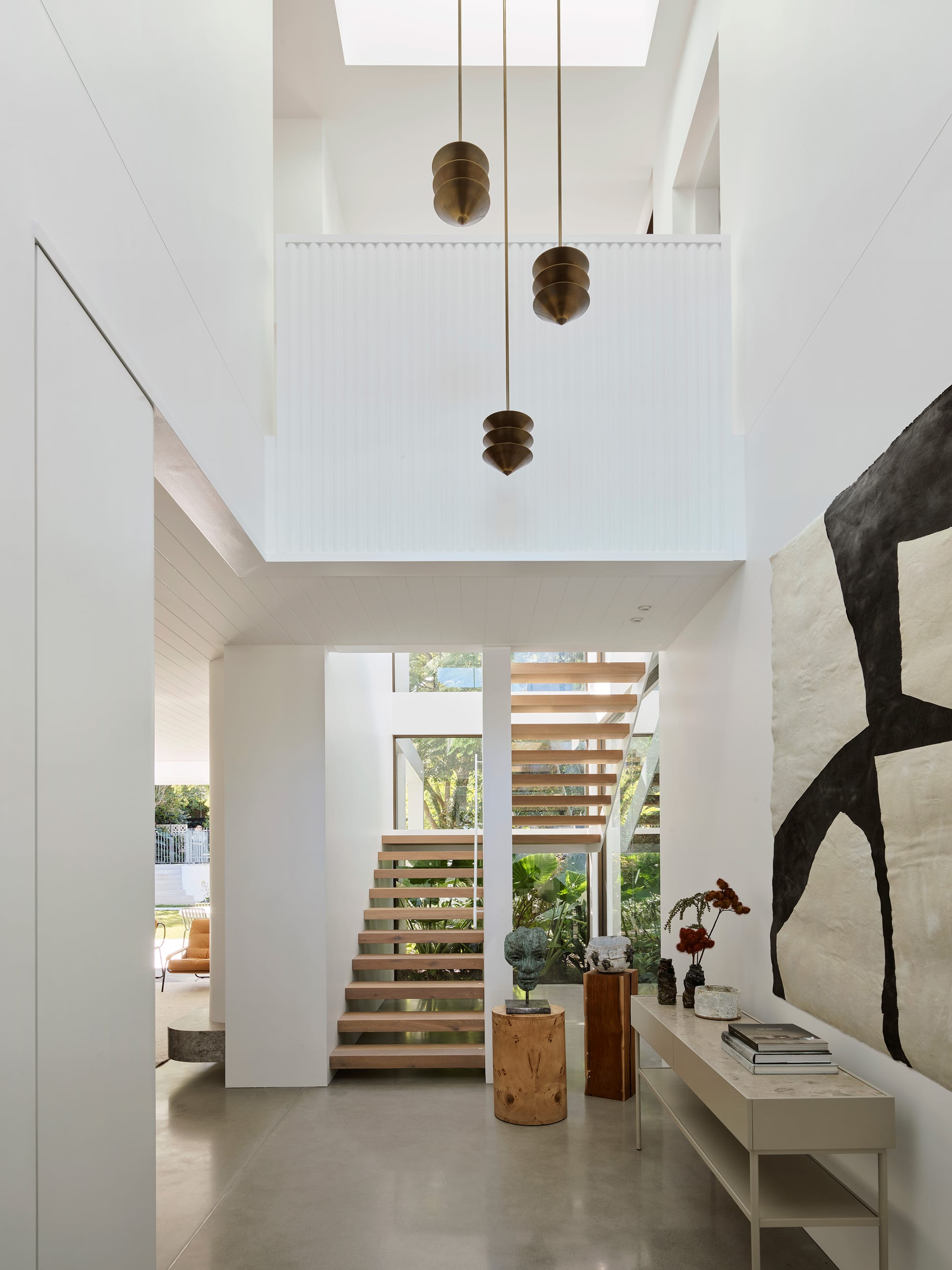 Warren House by CM Studio. Photography by Nic Gossage. Contemporary white and timber staircase. Polished concrete floors and white walls. Large void overhead.