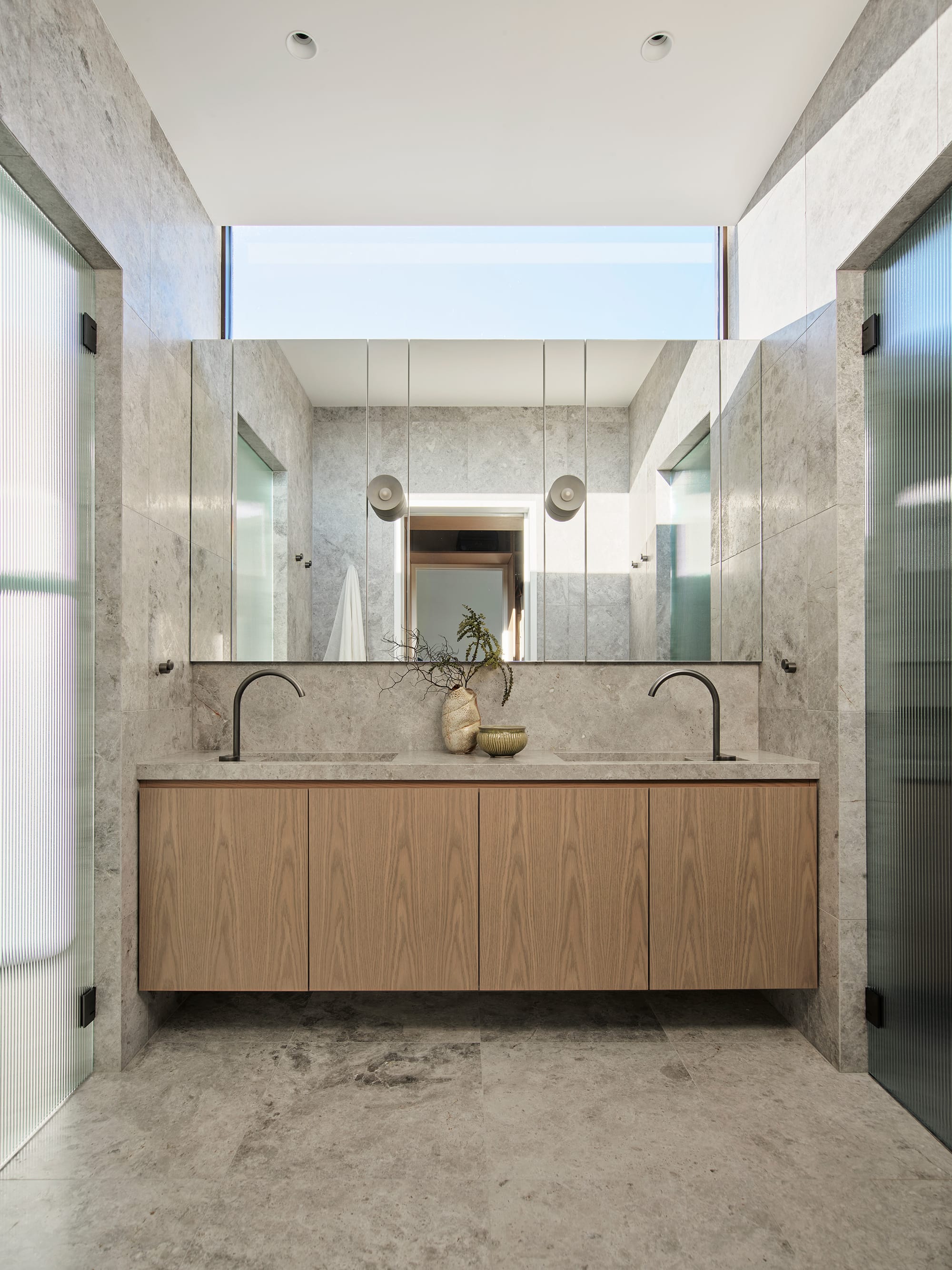 Warren House by CM Studio. Photography by Nic Gossage. Bathroom with grey tiles on floor and wall. Timber counter with double sink. 