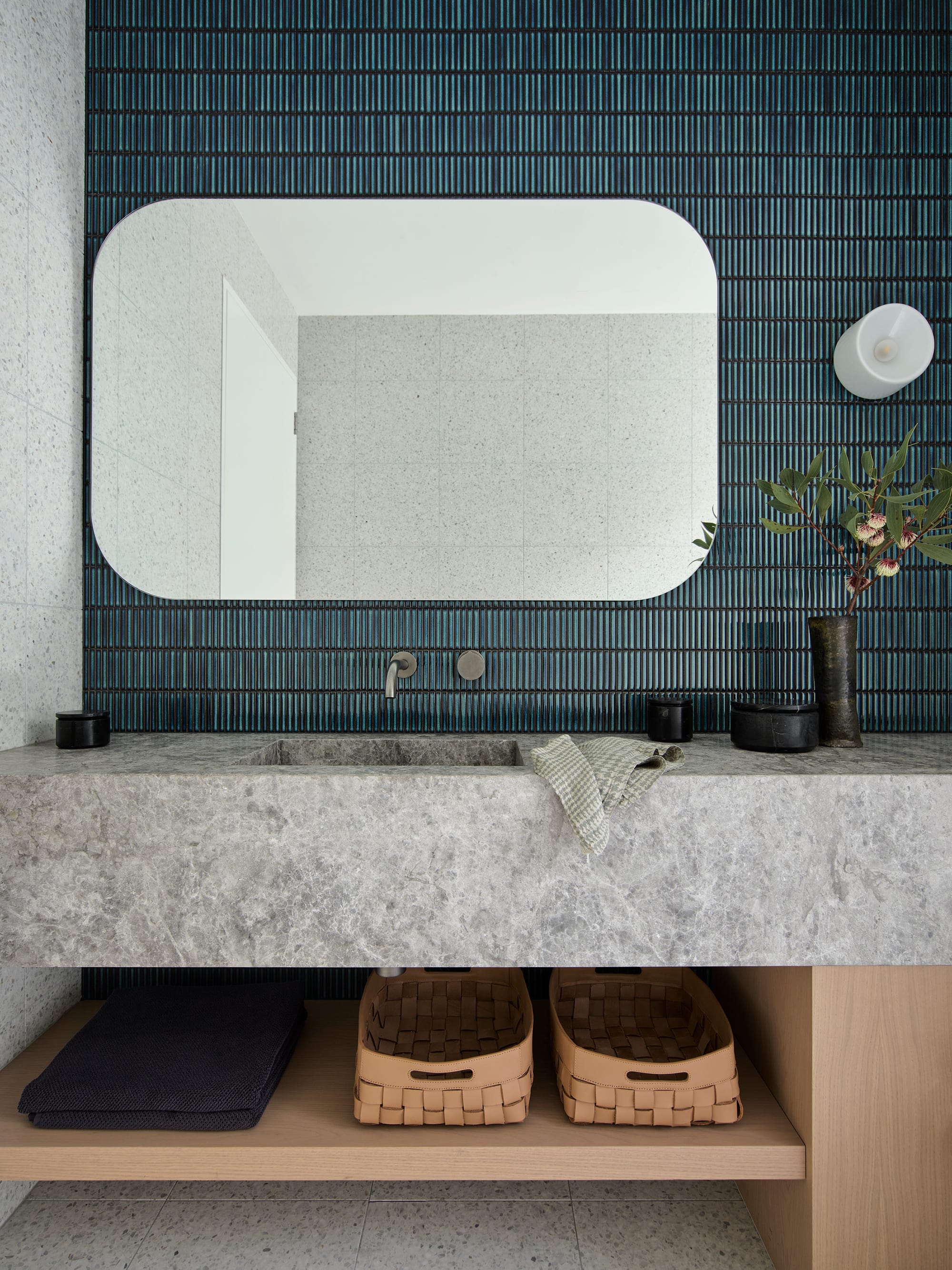 Warren House by CM Studio. Photography by Nic Gossage. Bathroom counter with grey stone countertop, blue finger tiles and timber counter. Open shelving and floating mirror.