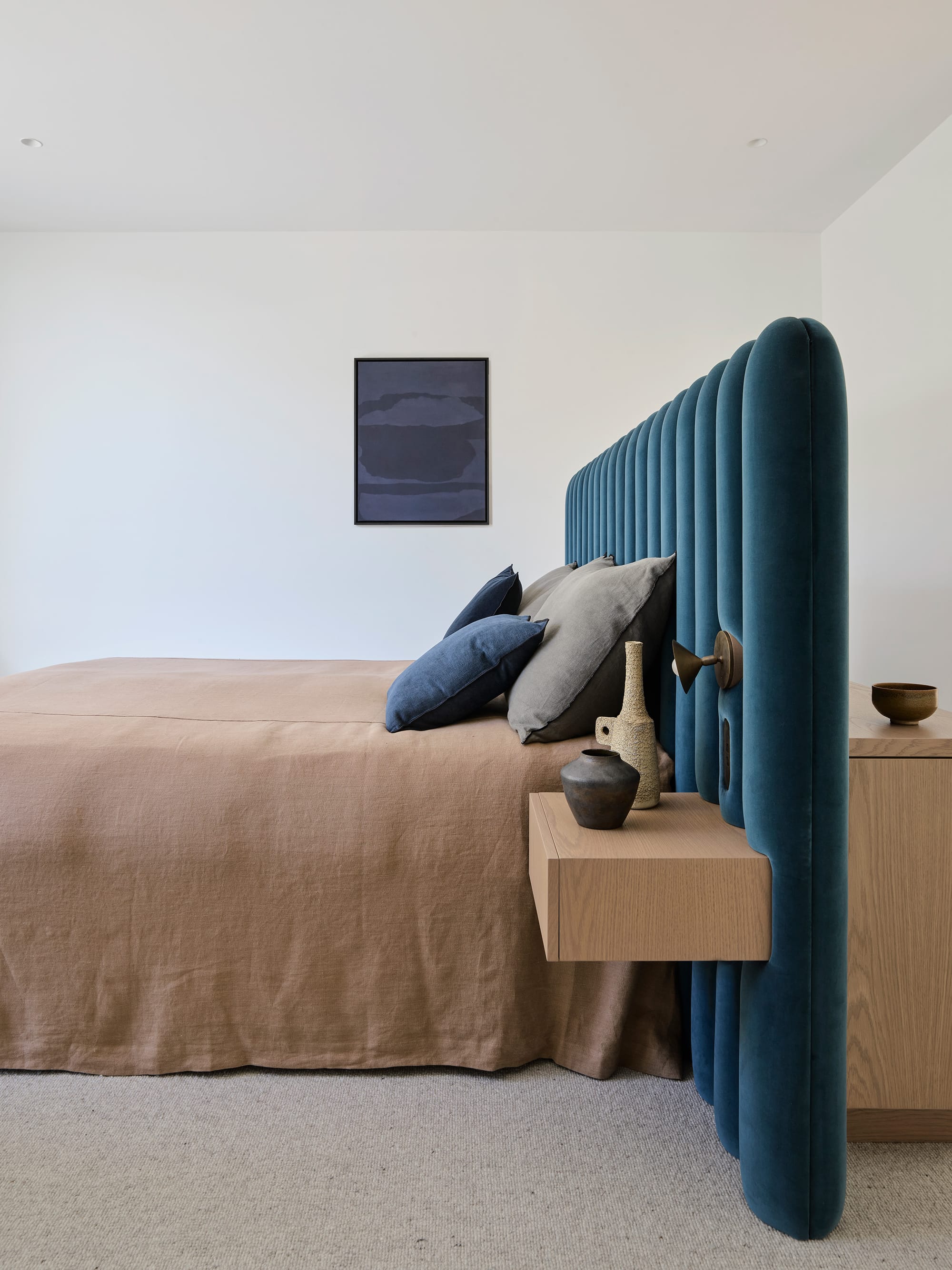 Warren House by CM Studio. Photography by Nic Gossage. Bedroom with teal velvet headboard and integrated timber bedside table. Brown bed cover.
