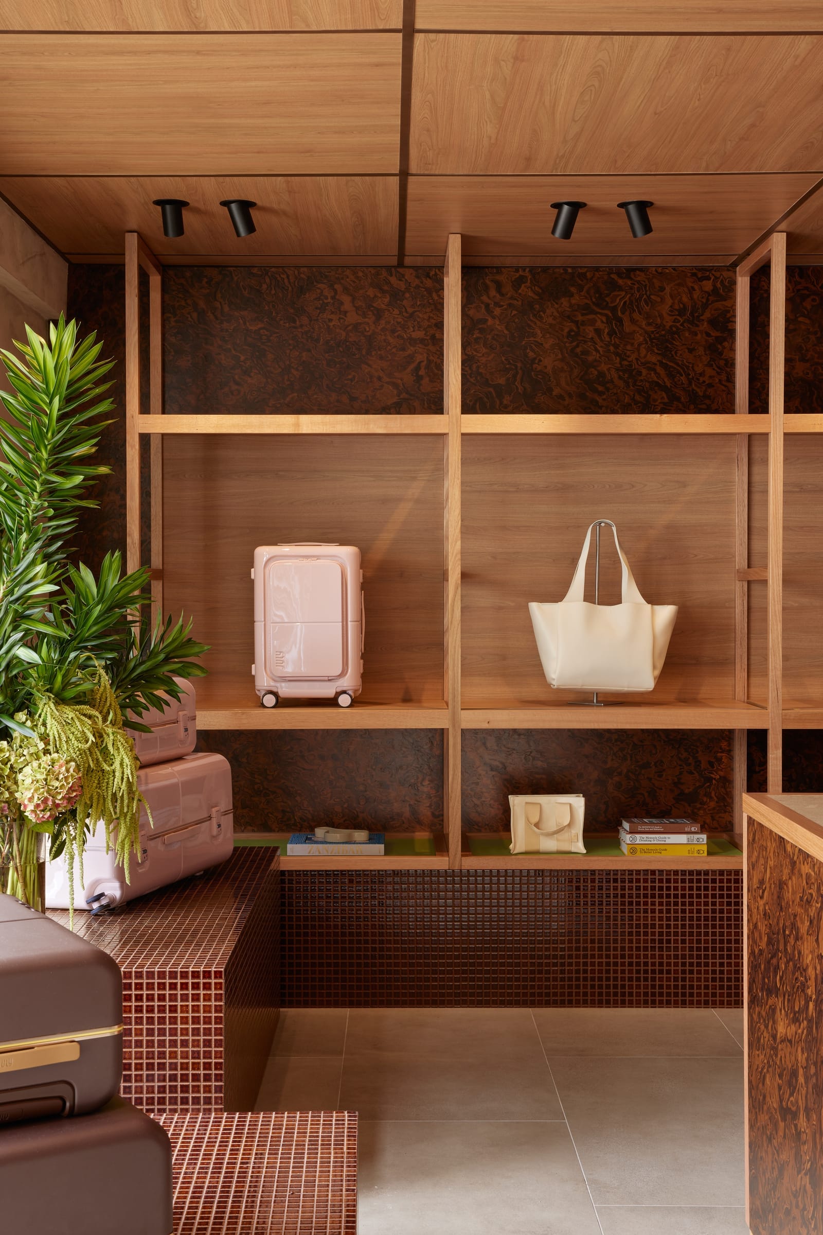 July Store by Acre. Photography by Cieran Murphy. Timber shelving unit. Maroon tiled walls and benches. Timber ceiling and grey tiled floor.  