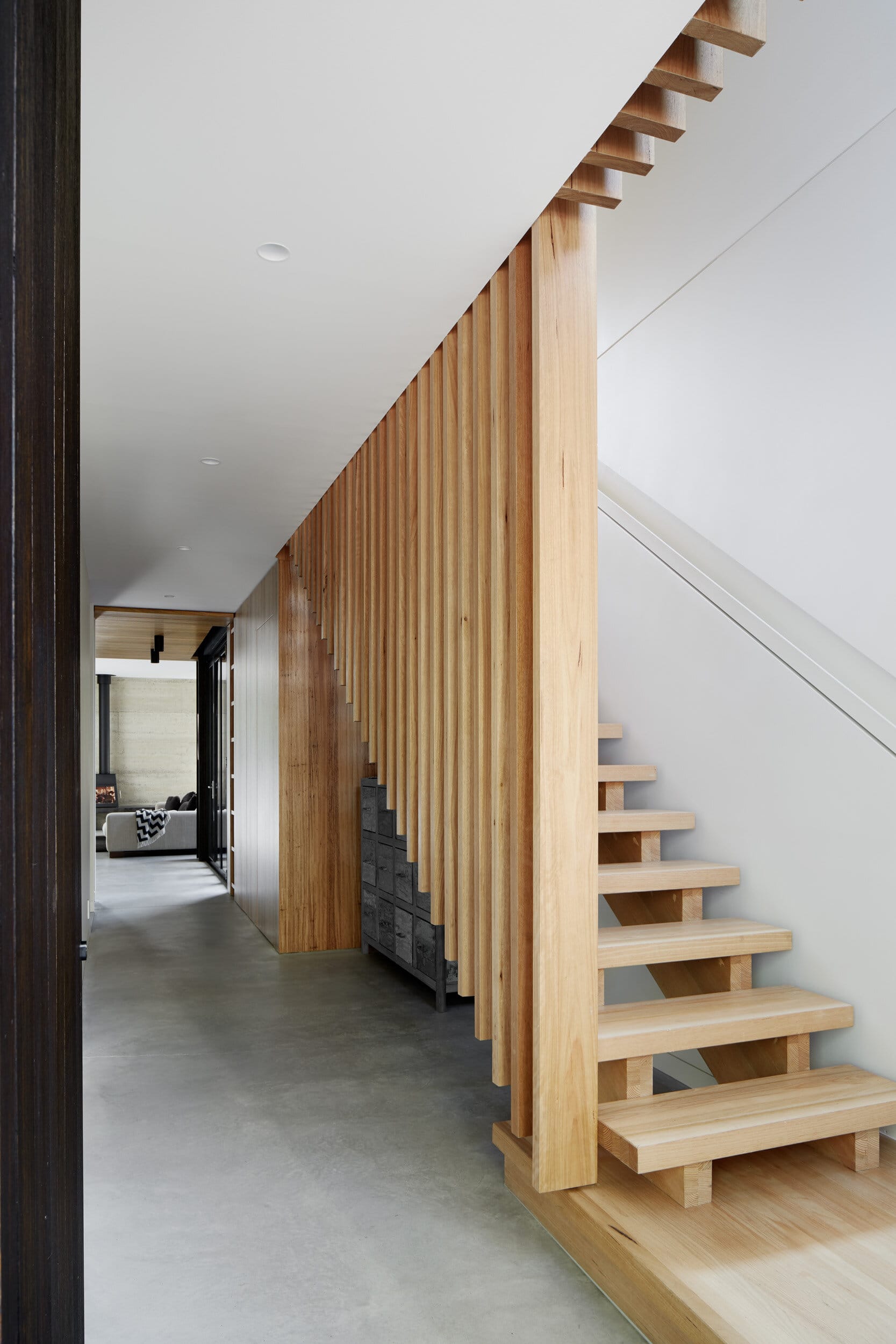 Laurel Grove by Kirsten Johnstone Architecture. Photography by Tatjana Plitt. Timber staircase with timber balustrade. Concrete floors on ground floor hallway. 