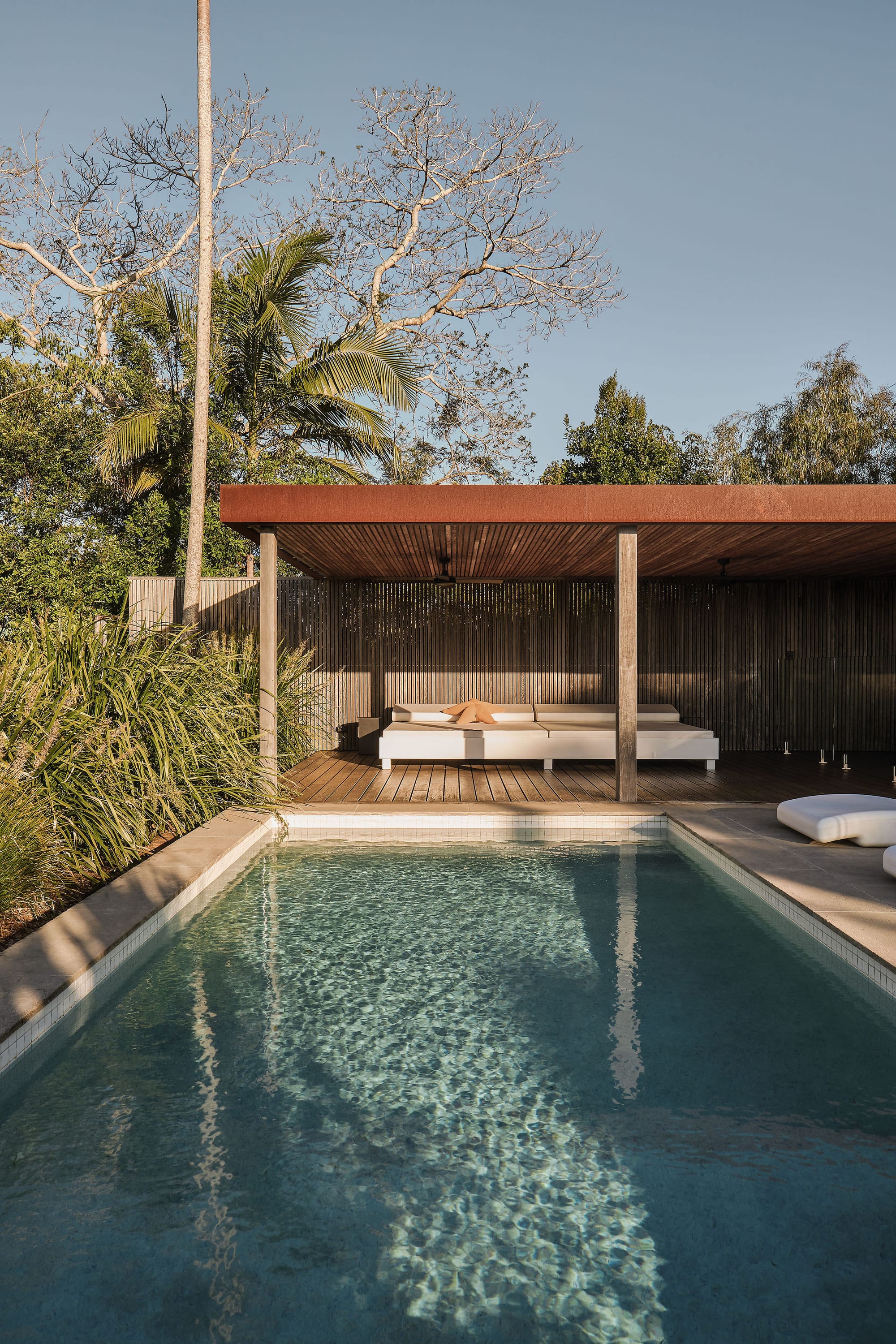 Rockpool Farm Byron Bay. Photography by Andy Macpherson. Outdoor pool with undercover timber patio with large white outdoor couch. 